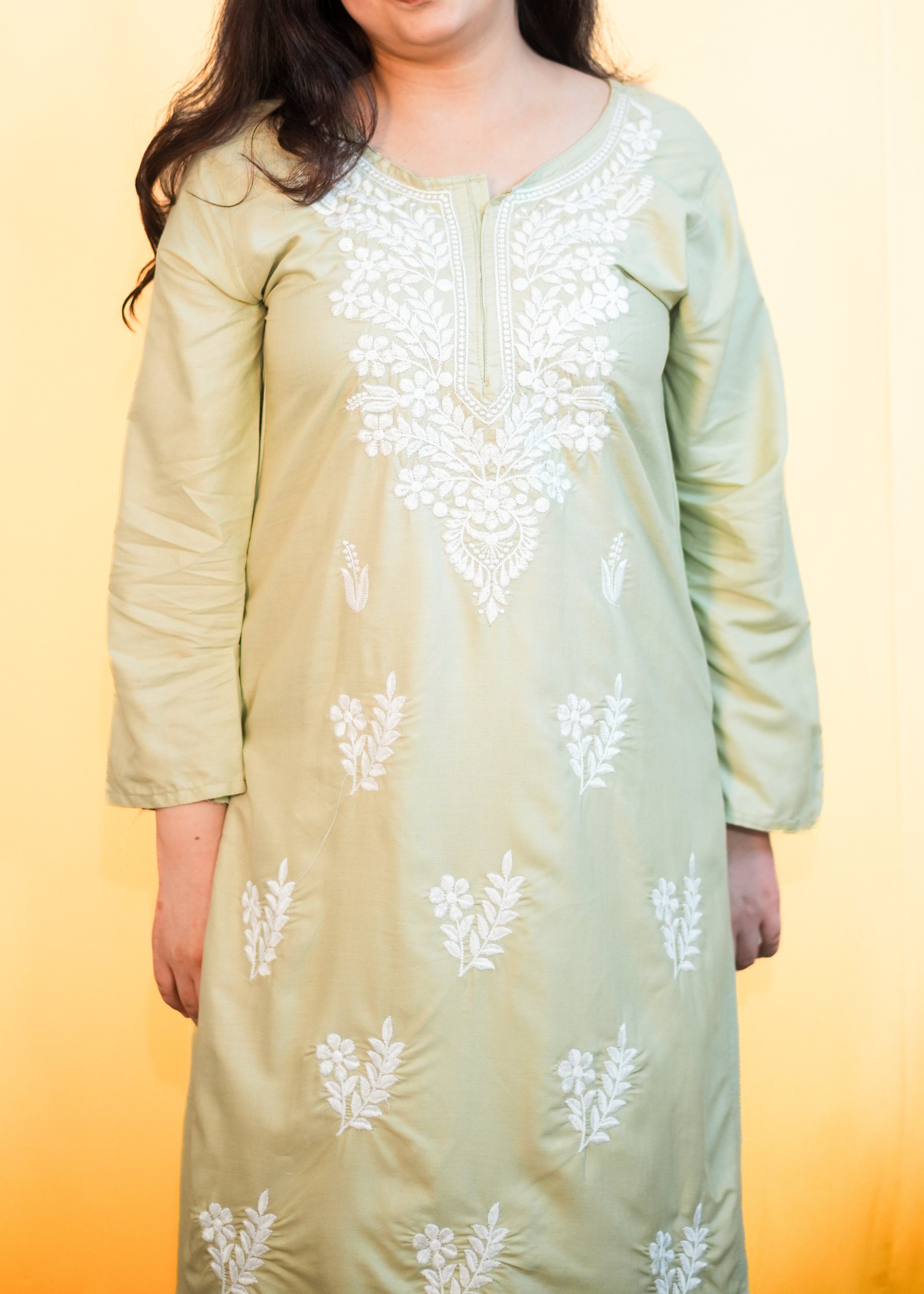Woman wearing a light green kurta with white floral patterns against a yellow background
