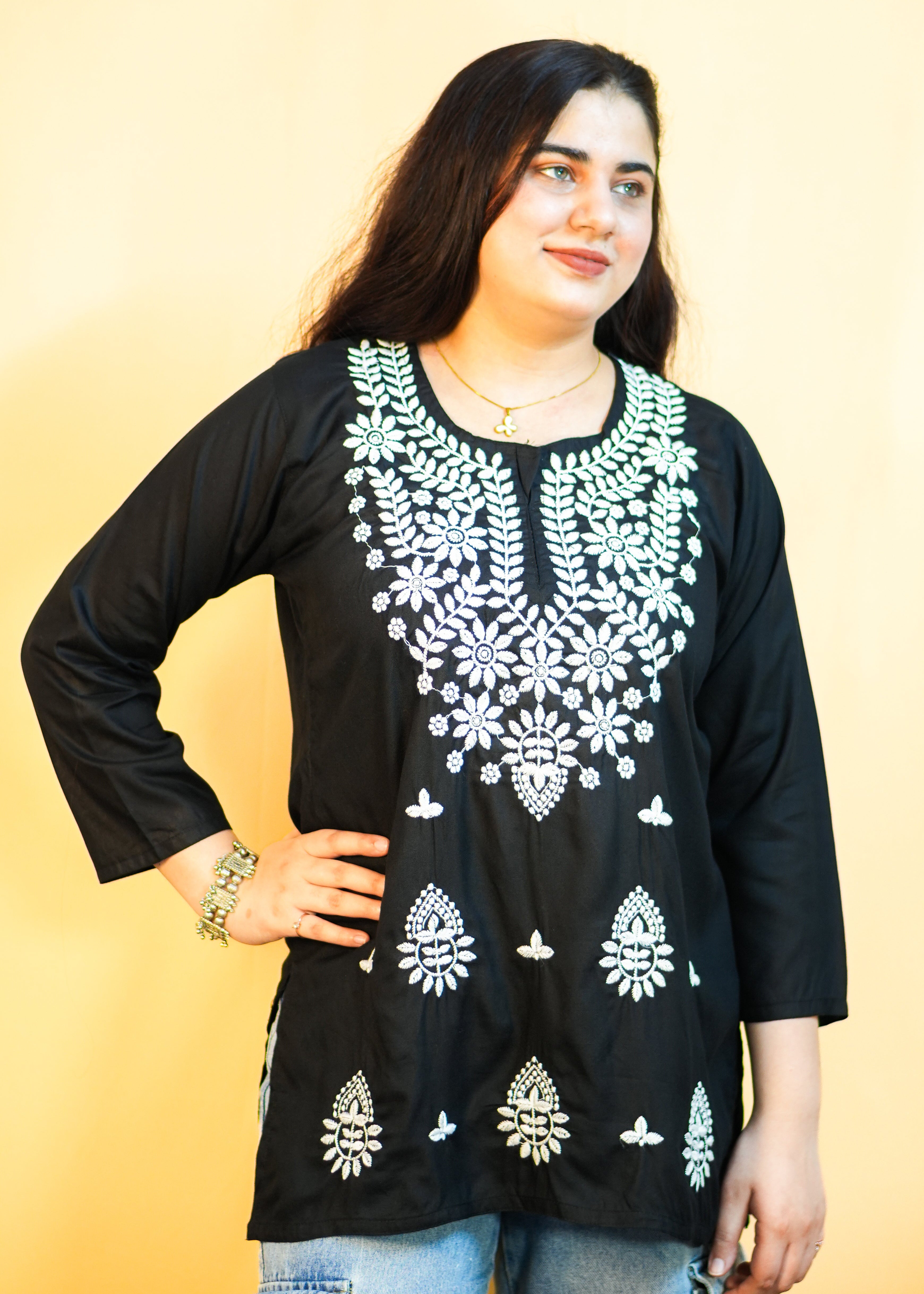Woman wearing a black embroidered top with a yellow background