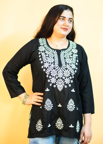 Woman wearing a black embroidered top with a yellow background