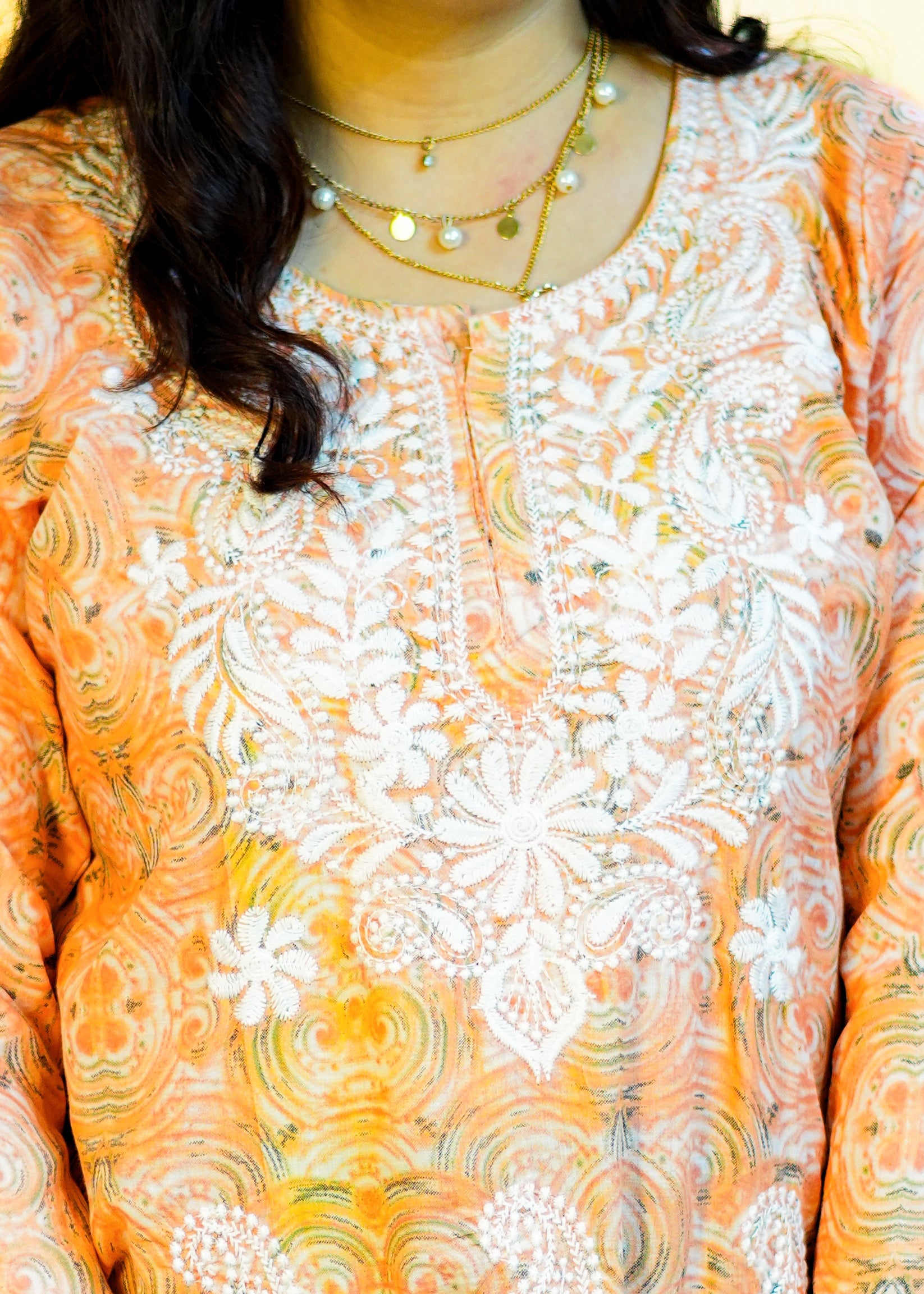 Woman wearing an orange and white patterned kurta against a yellow background