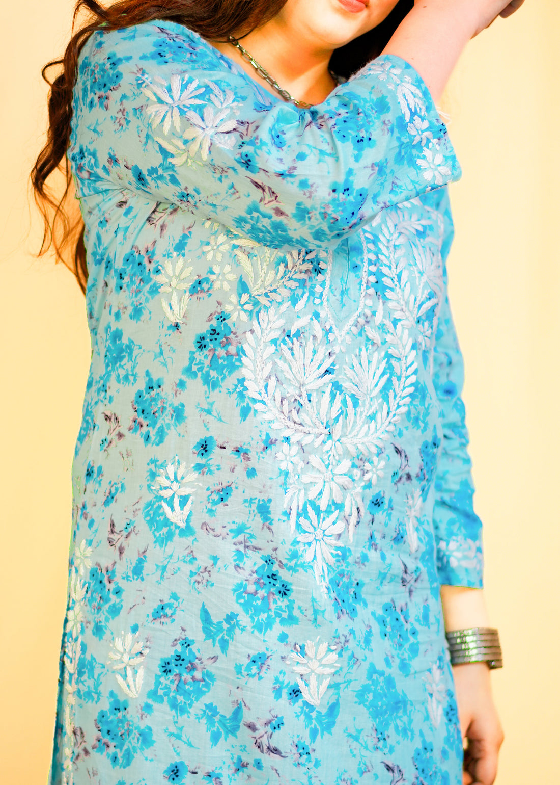Woman wearing a blue floral dress against a yellow background