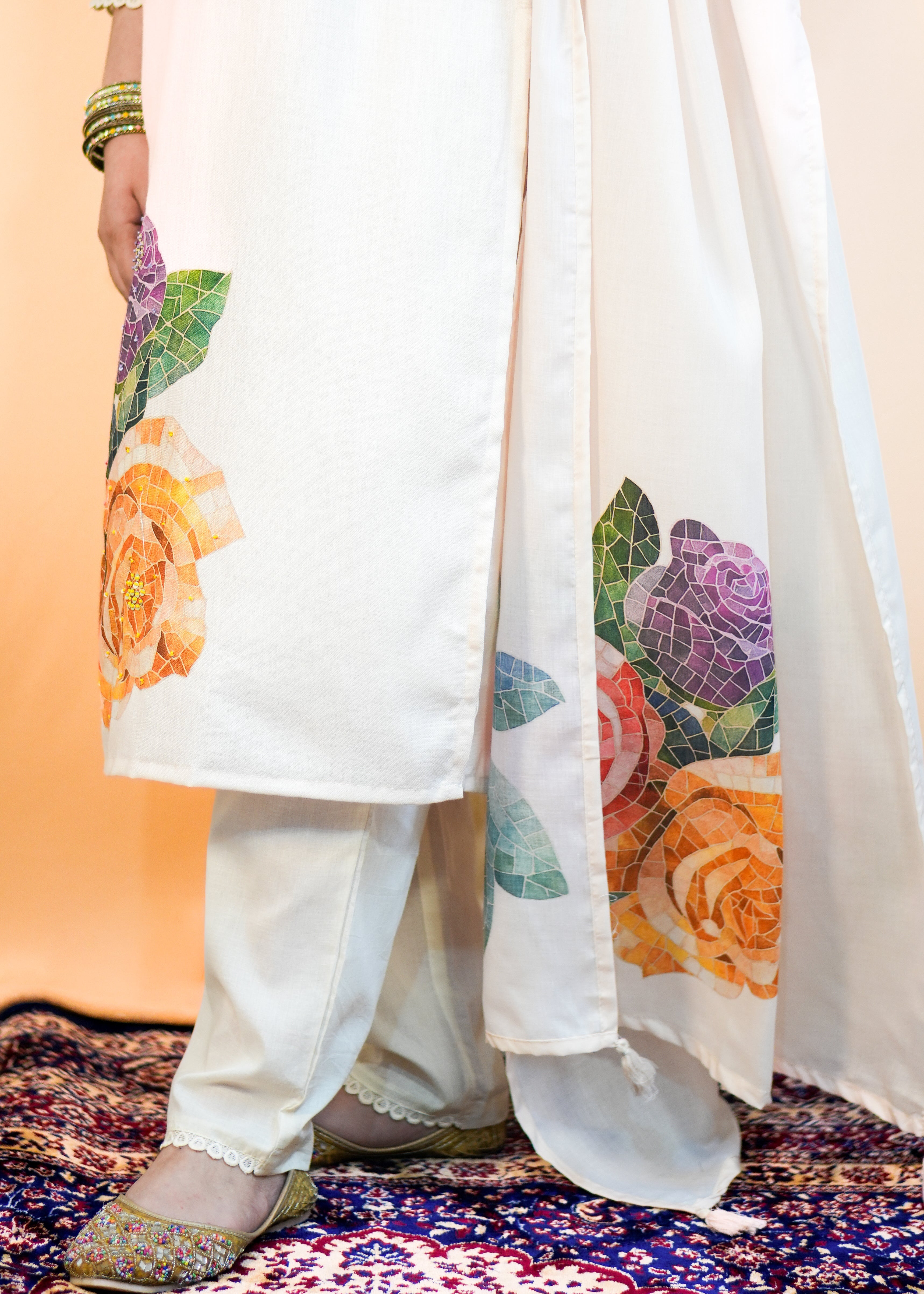 Person wearing a white outfit with floral patterns on a patterned carpet