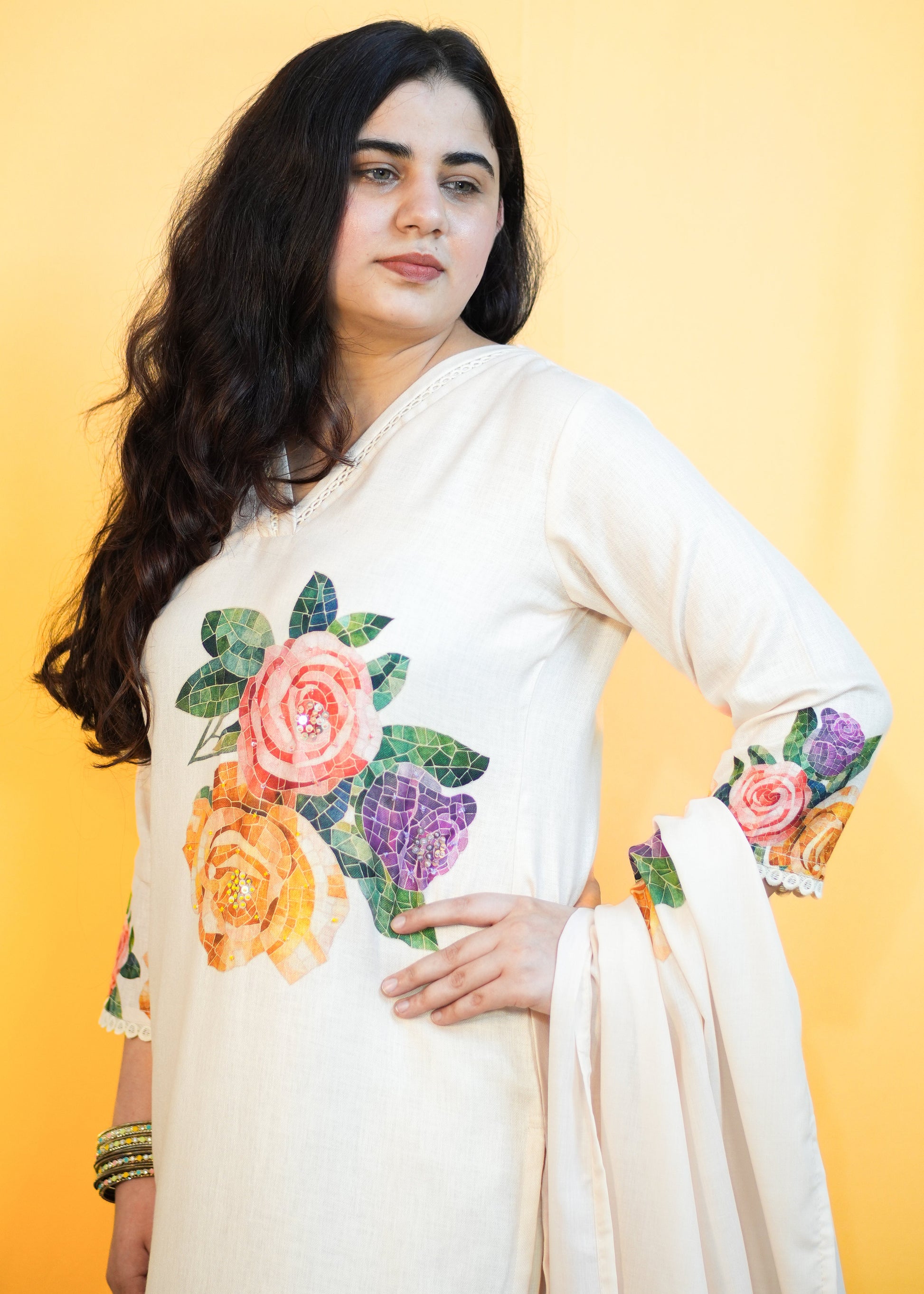 Woman wearing a white saree with floral patterns on a yellow background