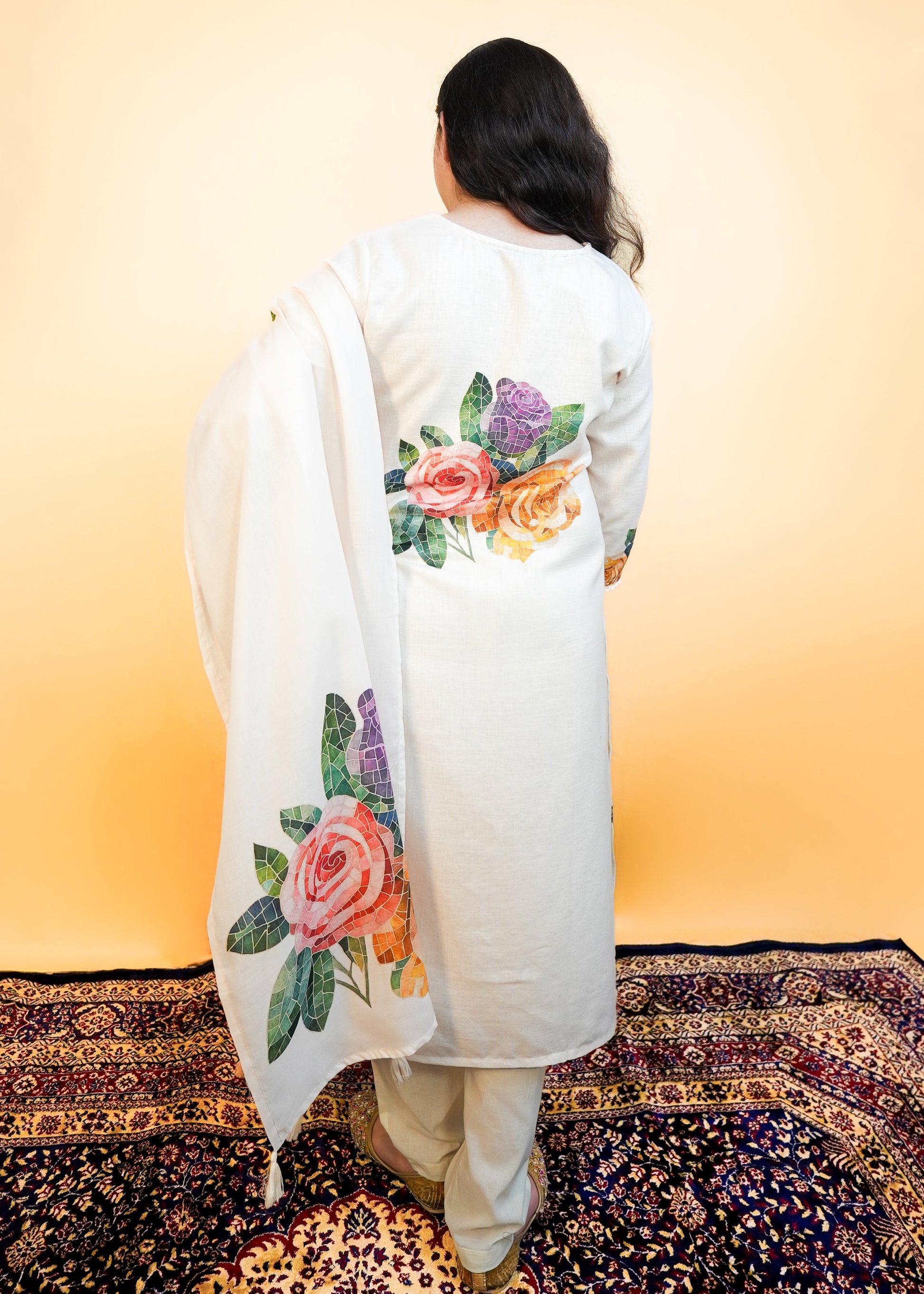 Person wearing a white embroidered garment on a patterned rug with a yellow wall background