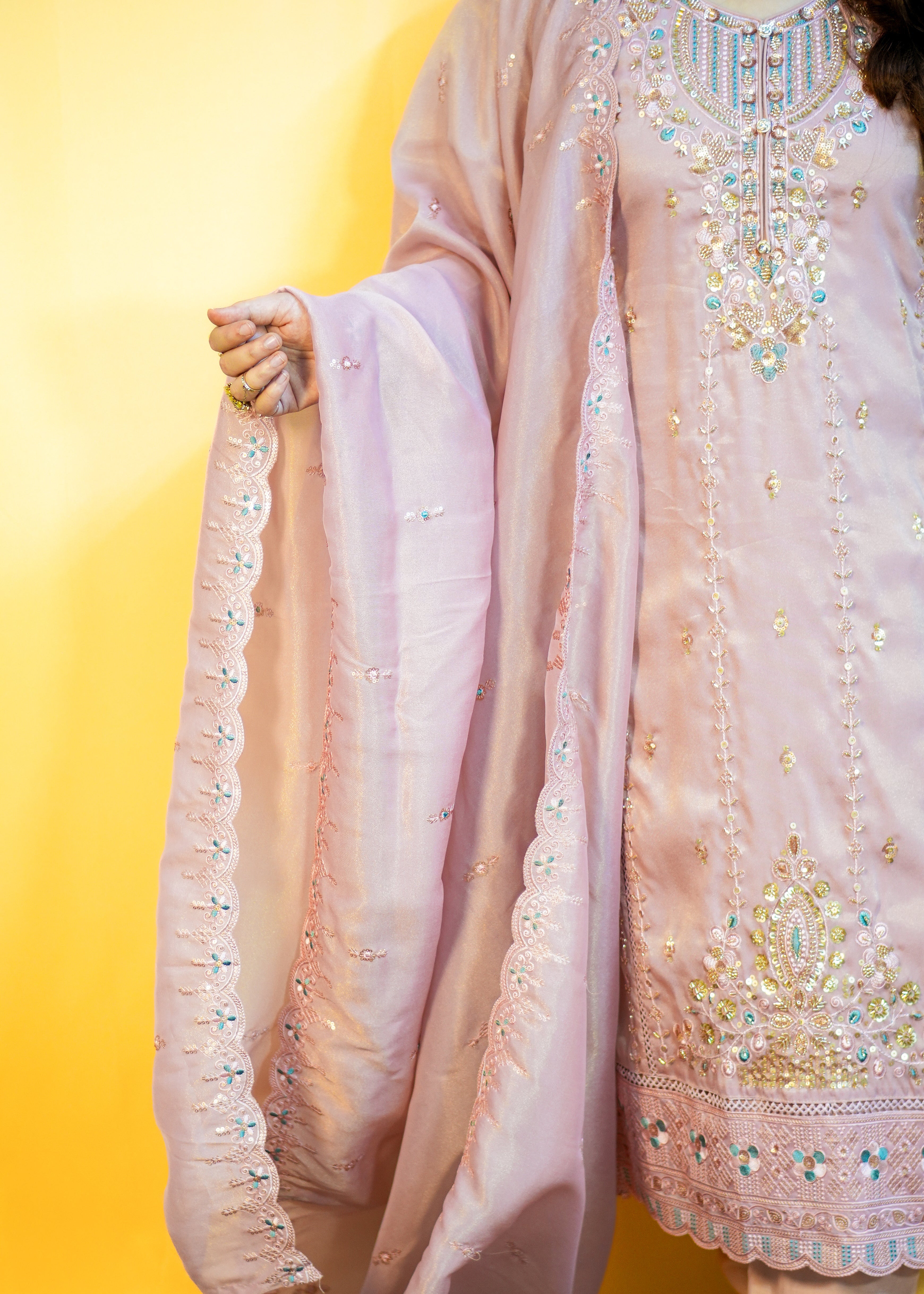 Light pink embroidered traditional outfit with a yellow background