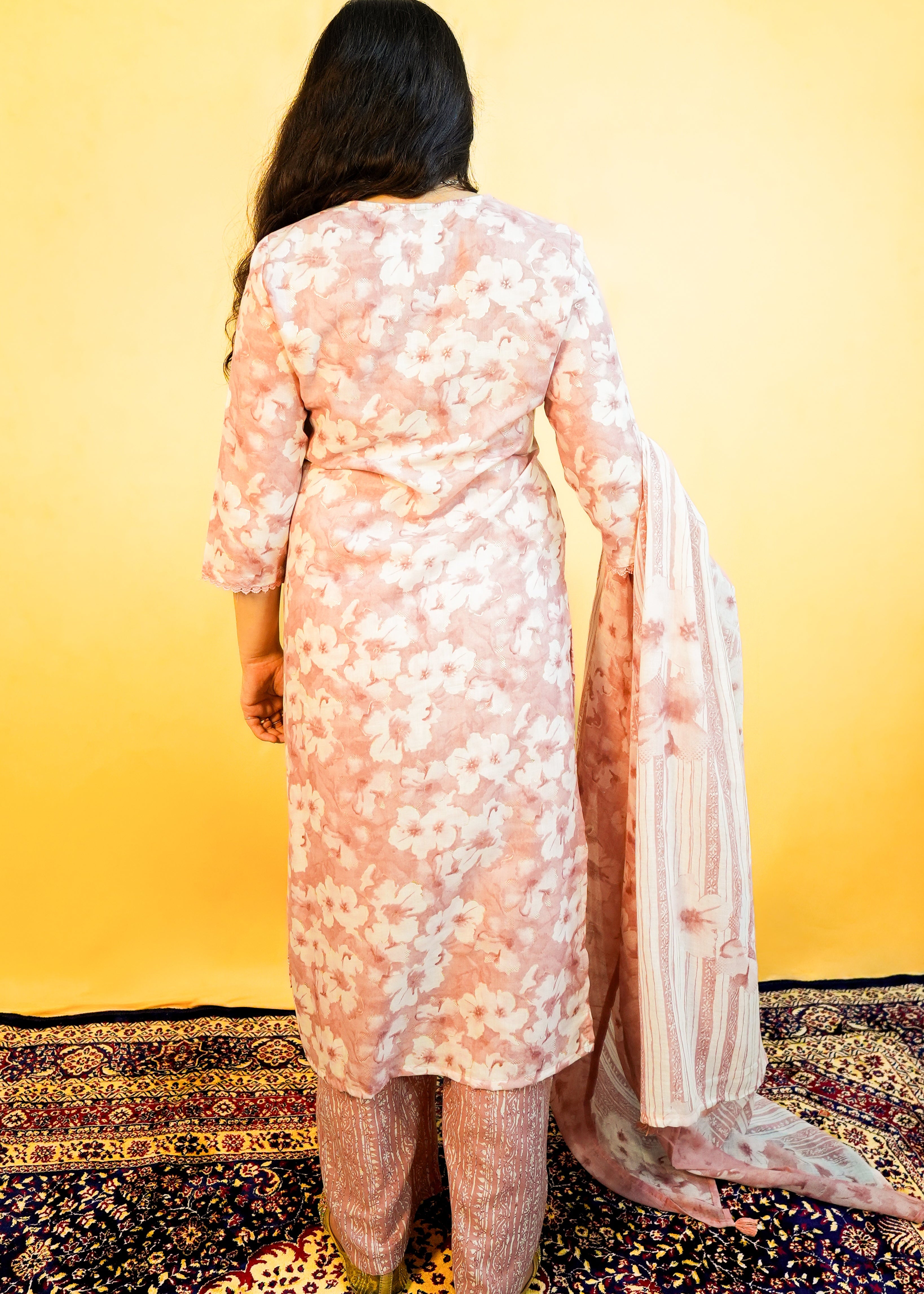 Person wearing a light pink floral dress with a yellow background