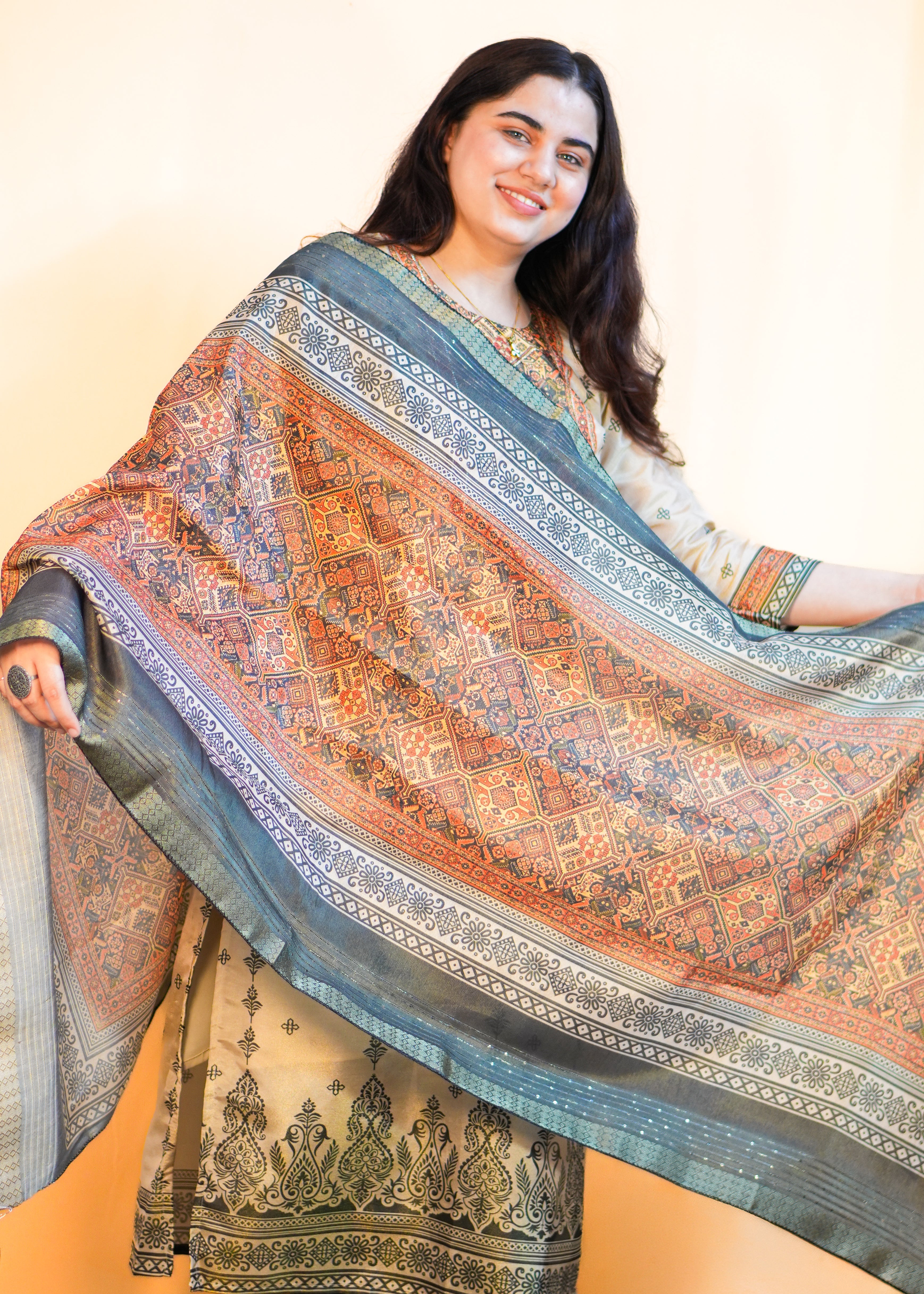 Woman holding a large, patterned shawl against a plain background