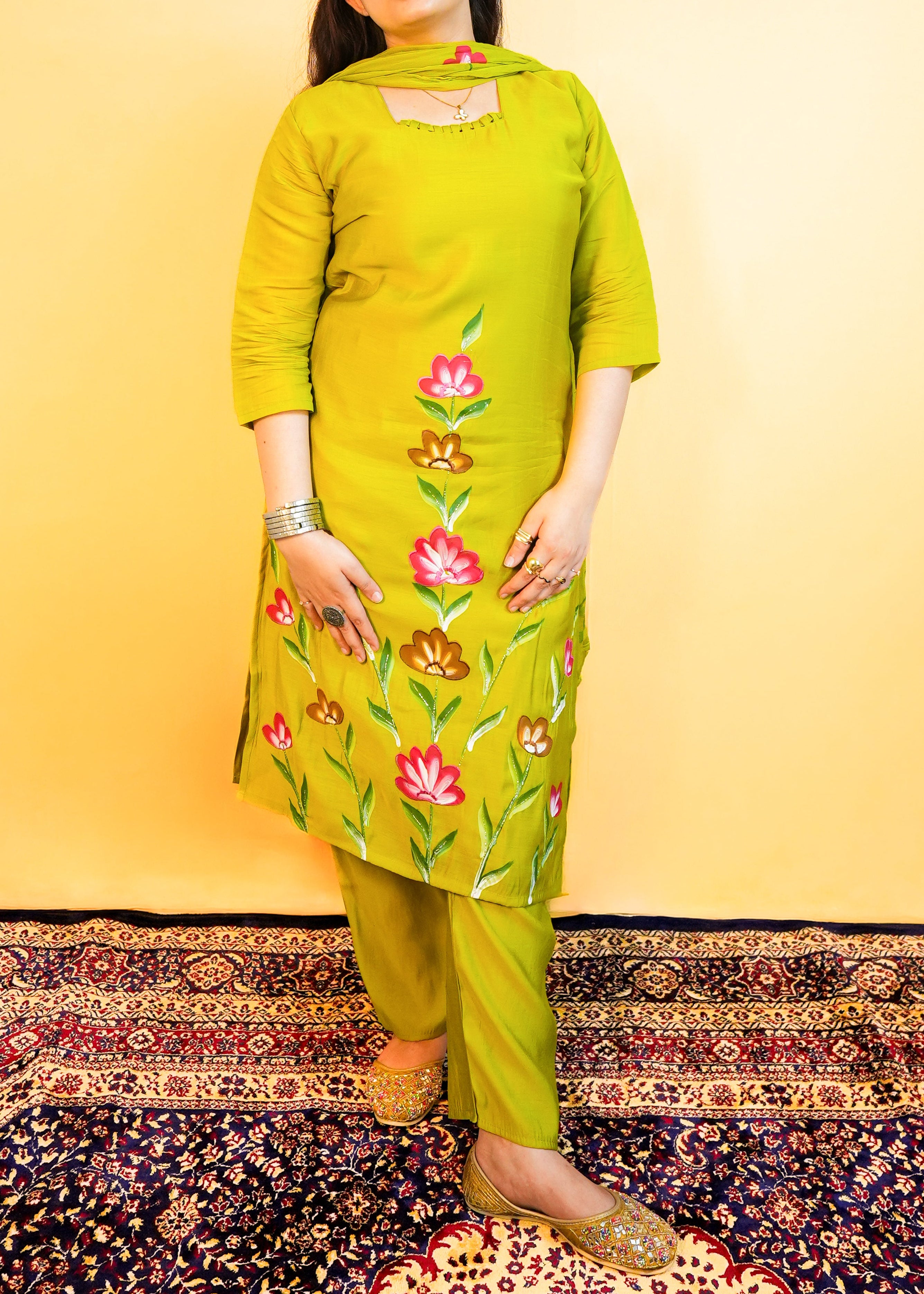 Woman wearing a green floral kurta with matching pants on a yellow background