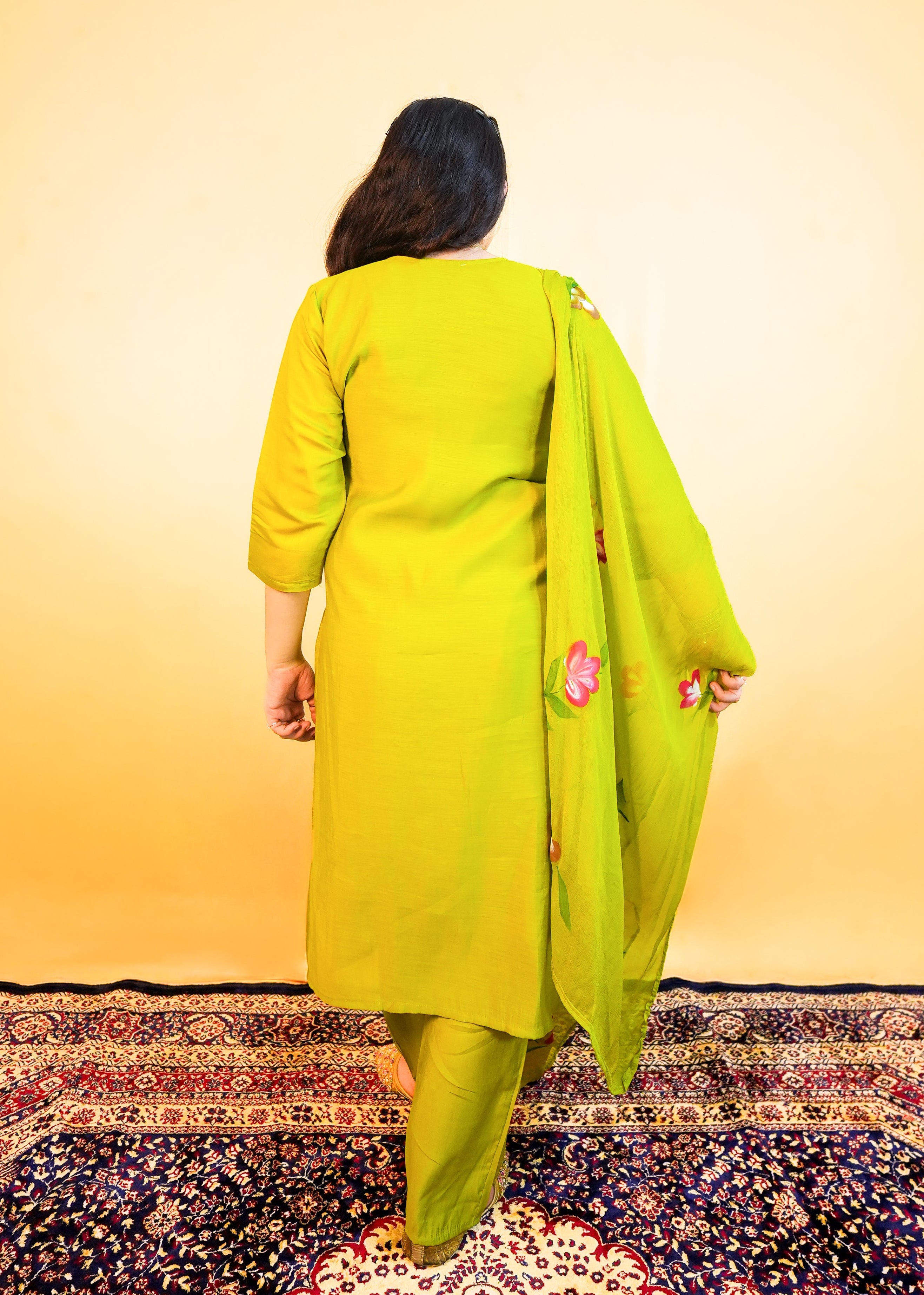 Person in a bright yellow outfit standing on a patterned rug with a gradient background