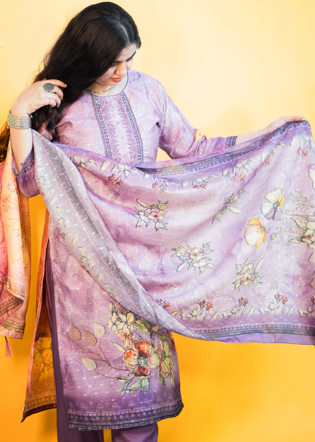 Woman holding a floral embroidered purple dupatta against a yellow background