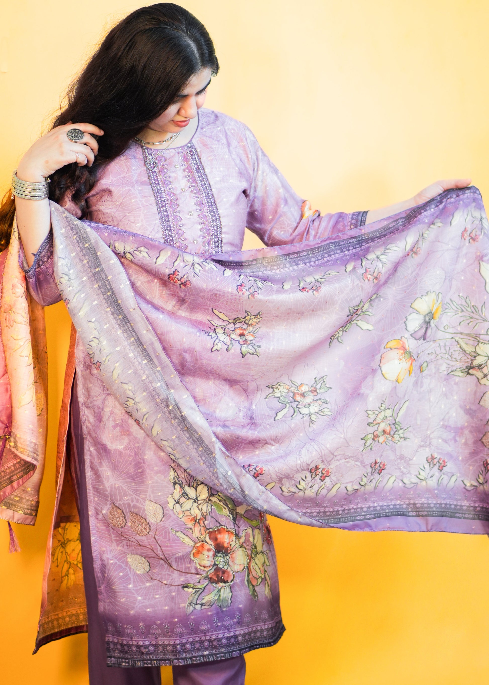 Woman holding a floral embroidered purple dupatta against a yellow background