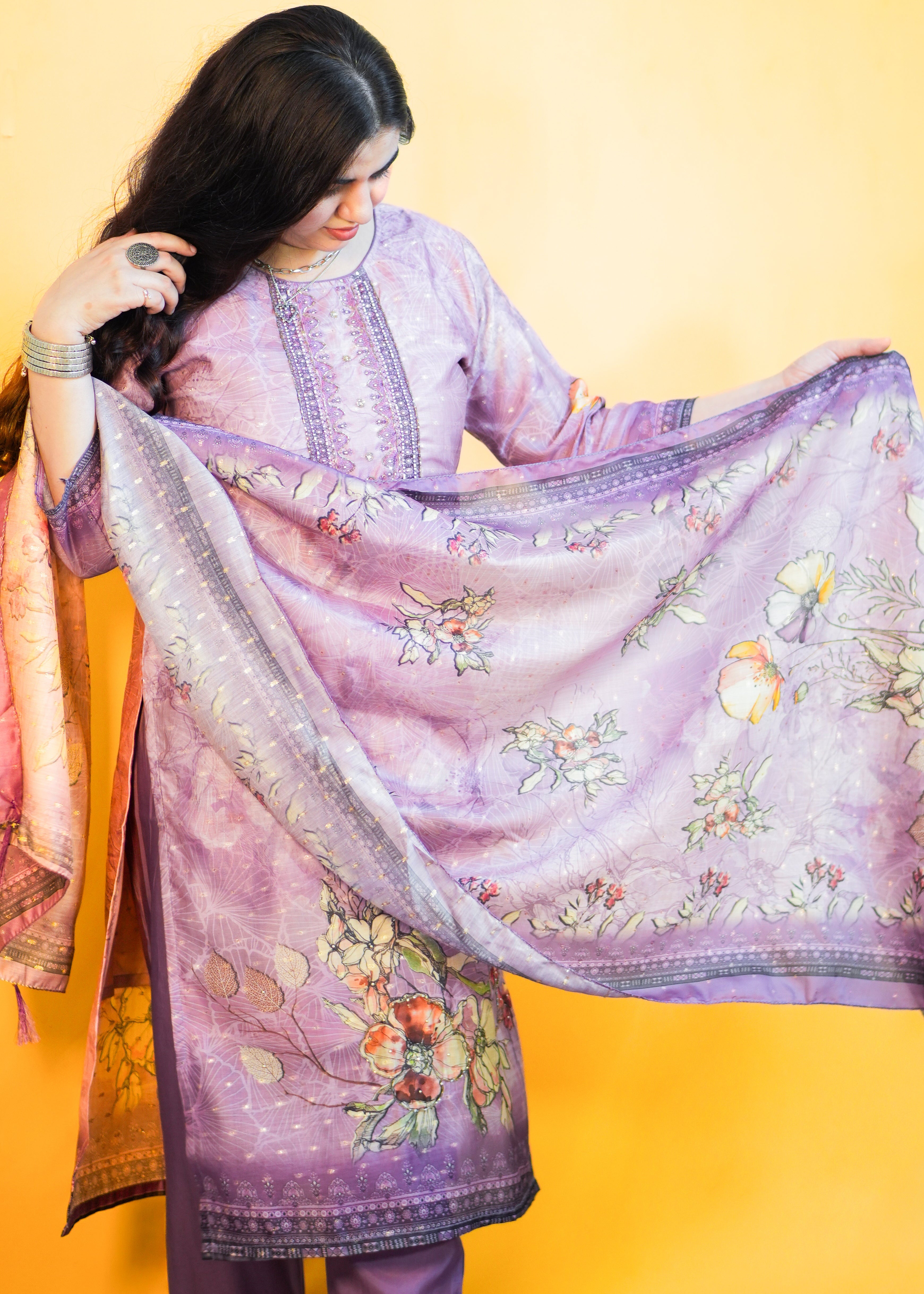 Woman holding a floral embroidered purple dupatta against a yellow background