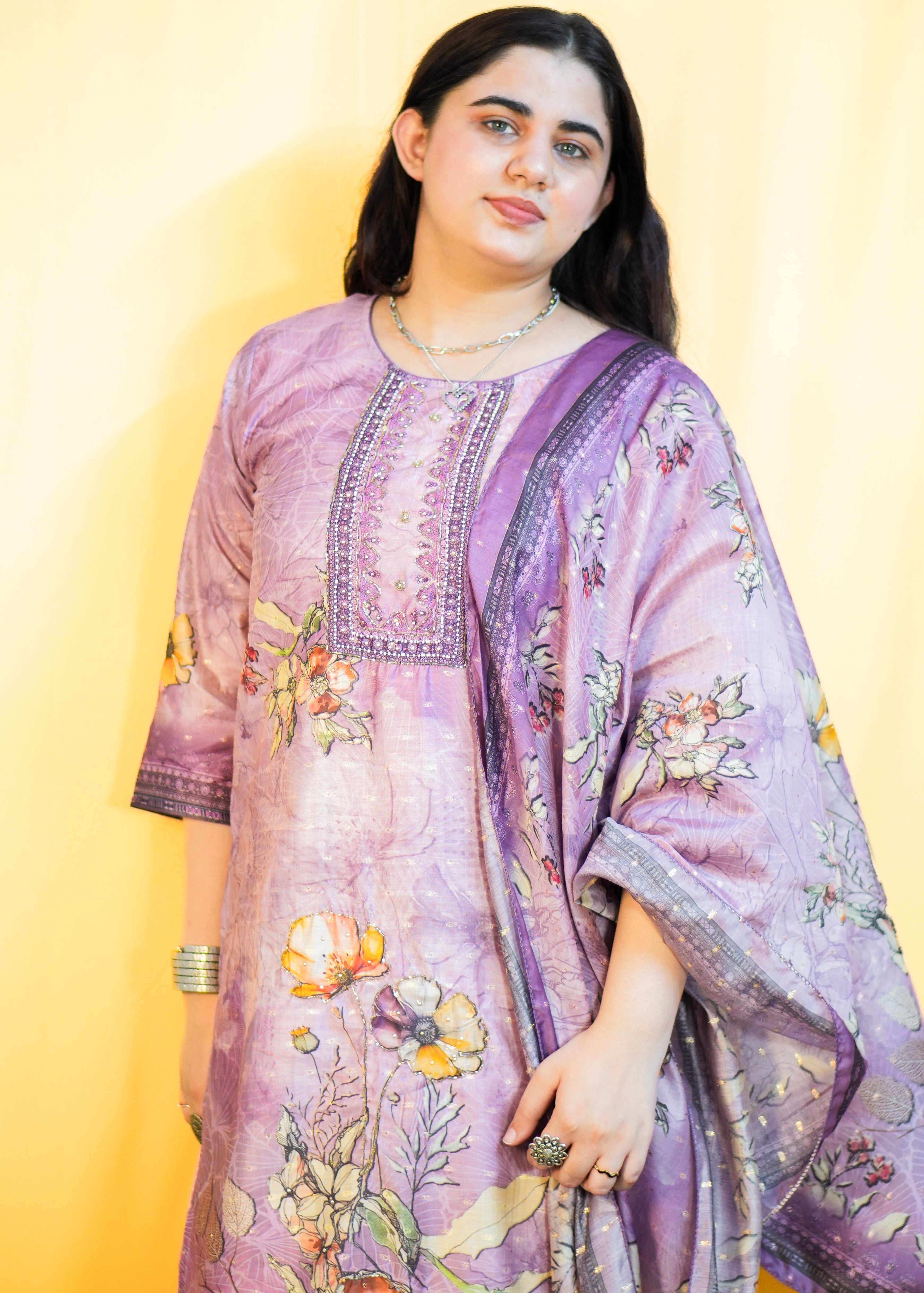 Woman wearing a purple floral embroidered outfit against a yellow background
