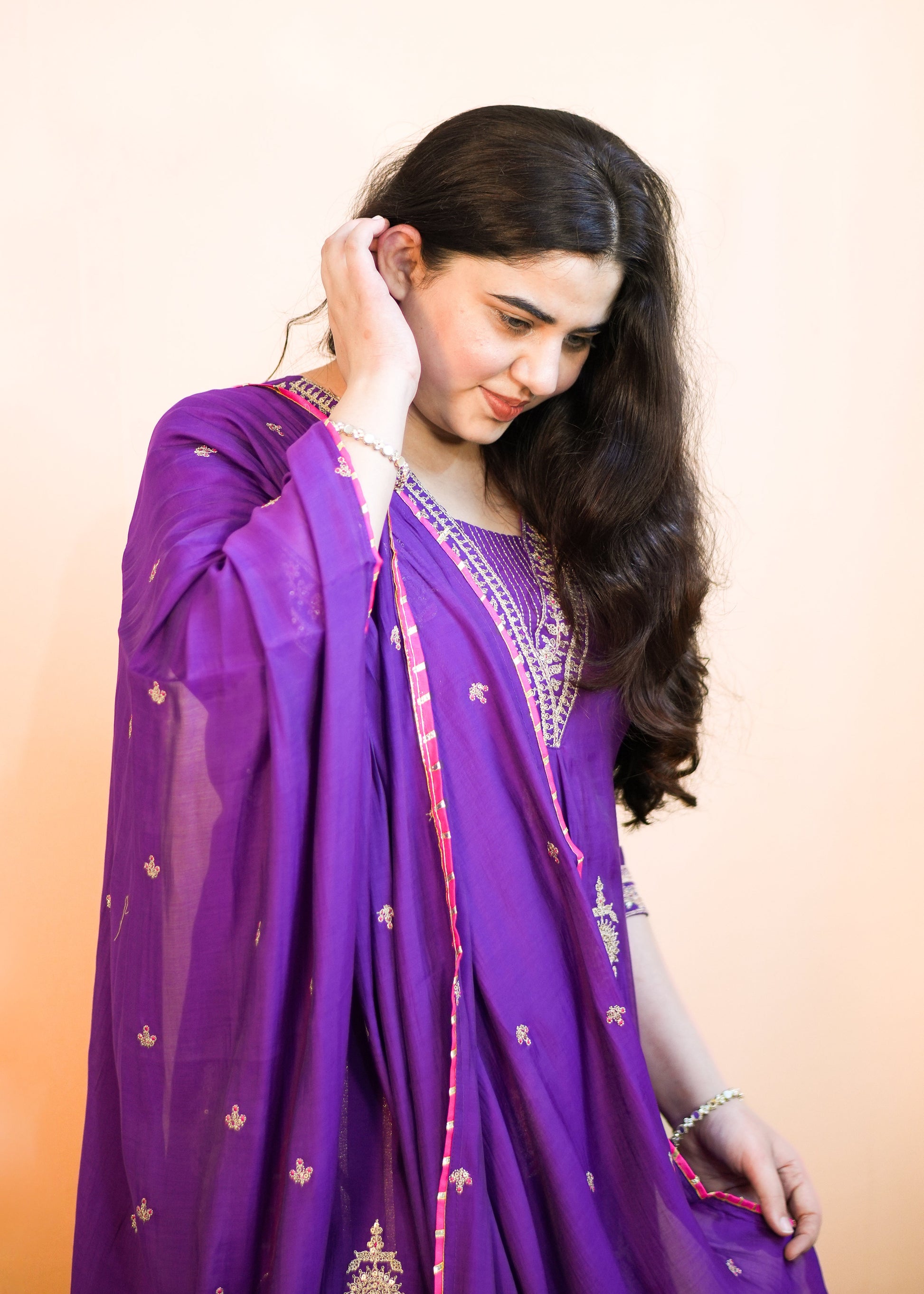 Woman wearing a purple traditional outfit with a plain background