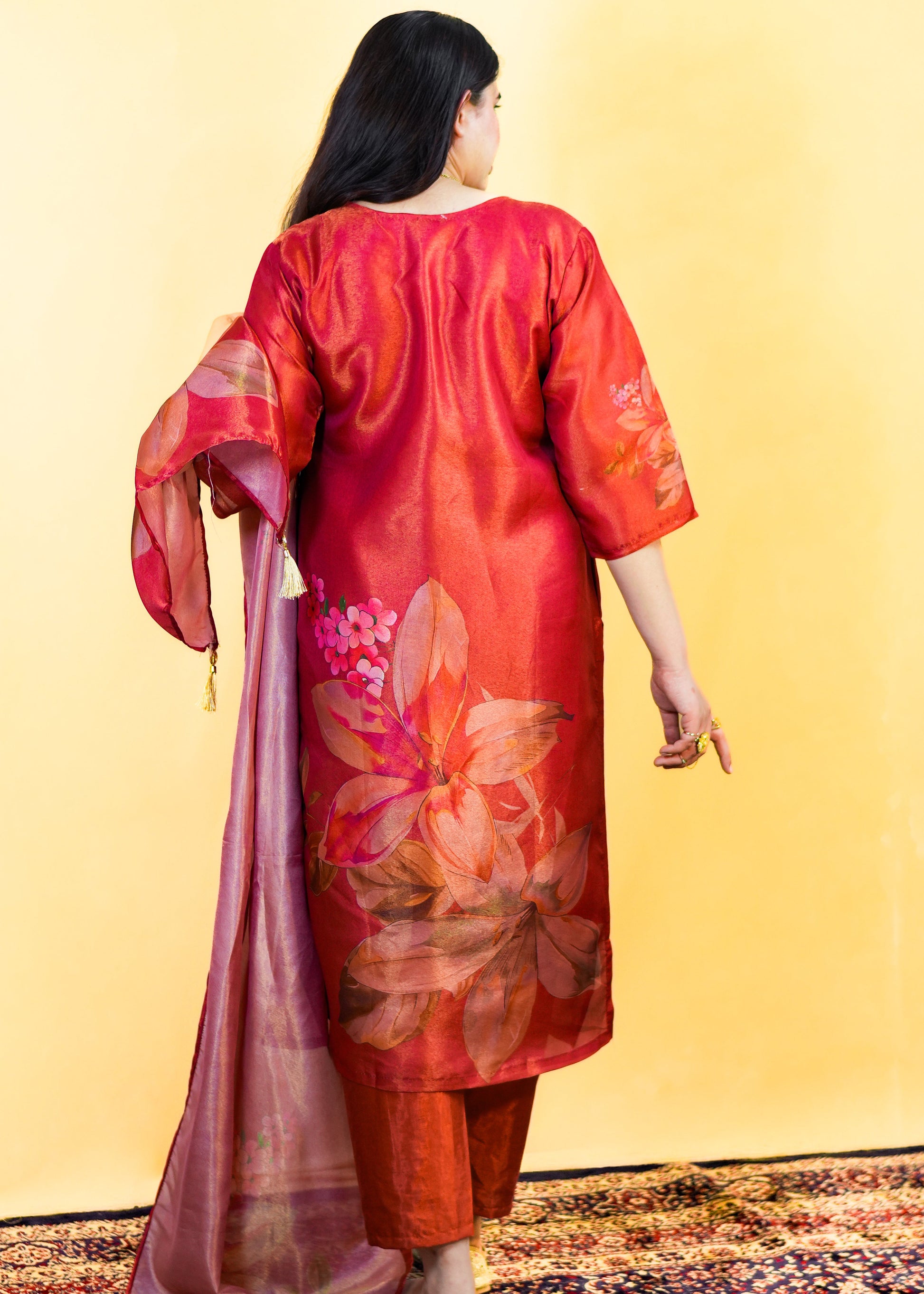 Woman wearing a red floral kurta with a dupatta on a yellow background
