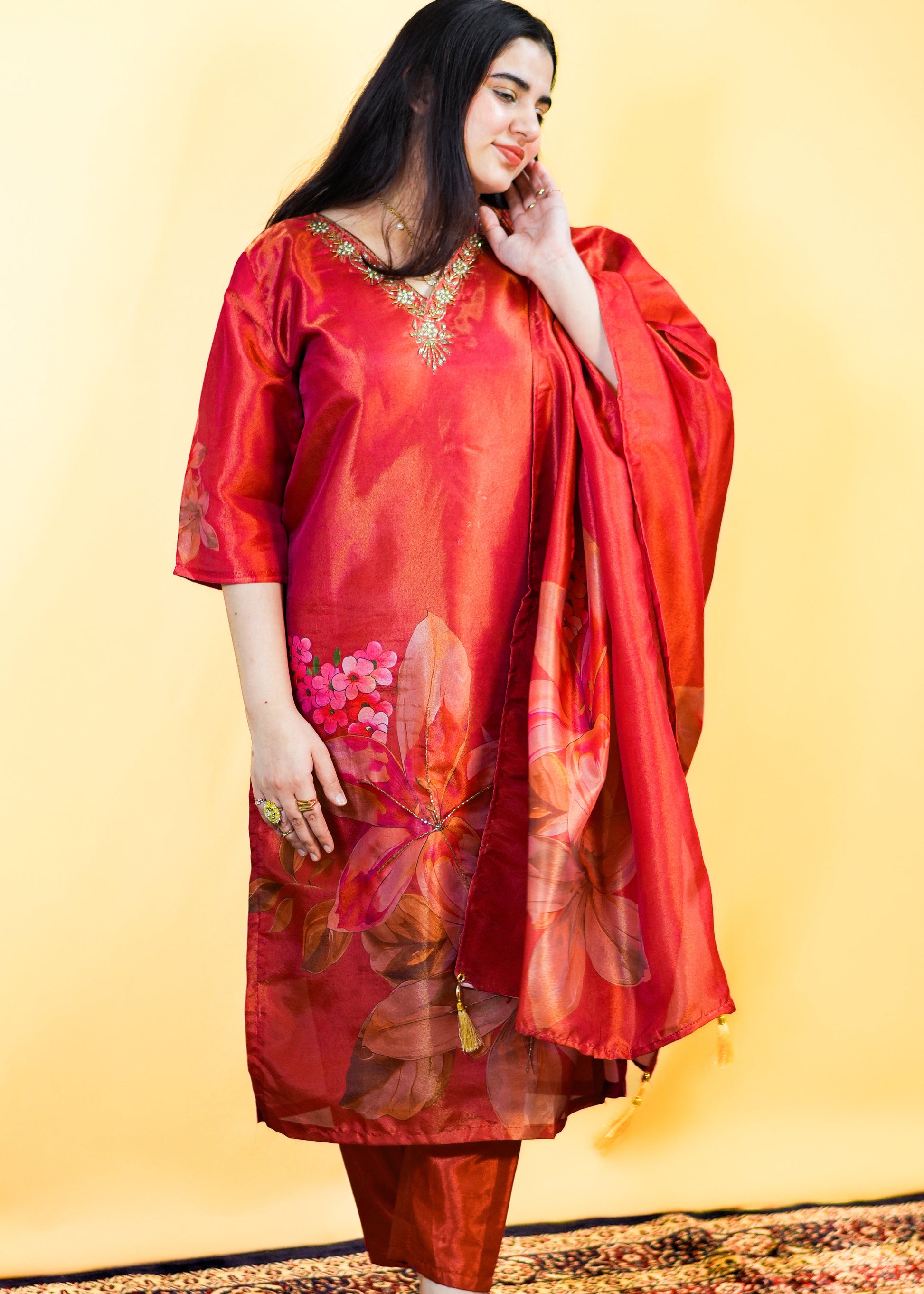 Woman in a red traditional outfit with floral patterns on a yellow background