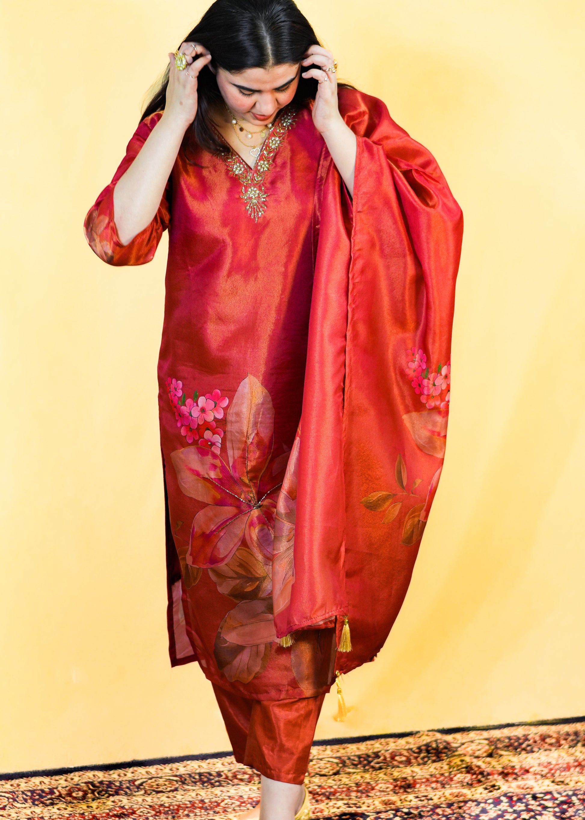 Woman in a red traditional outfit with floral patterns on a yellow background