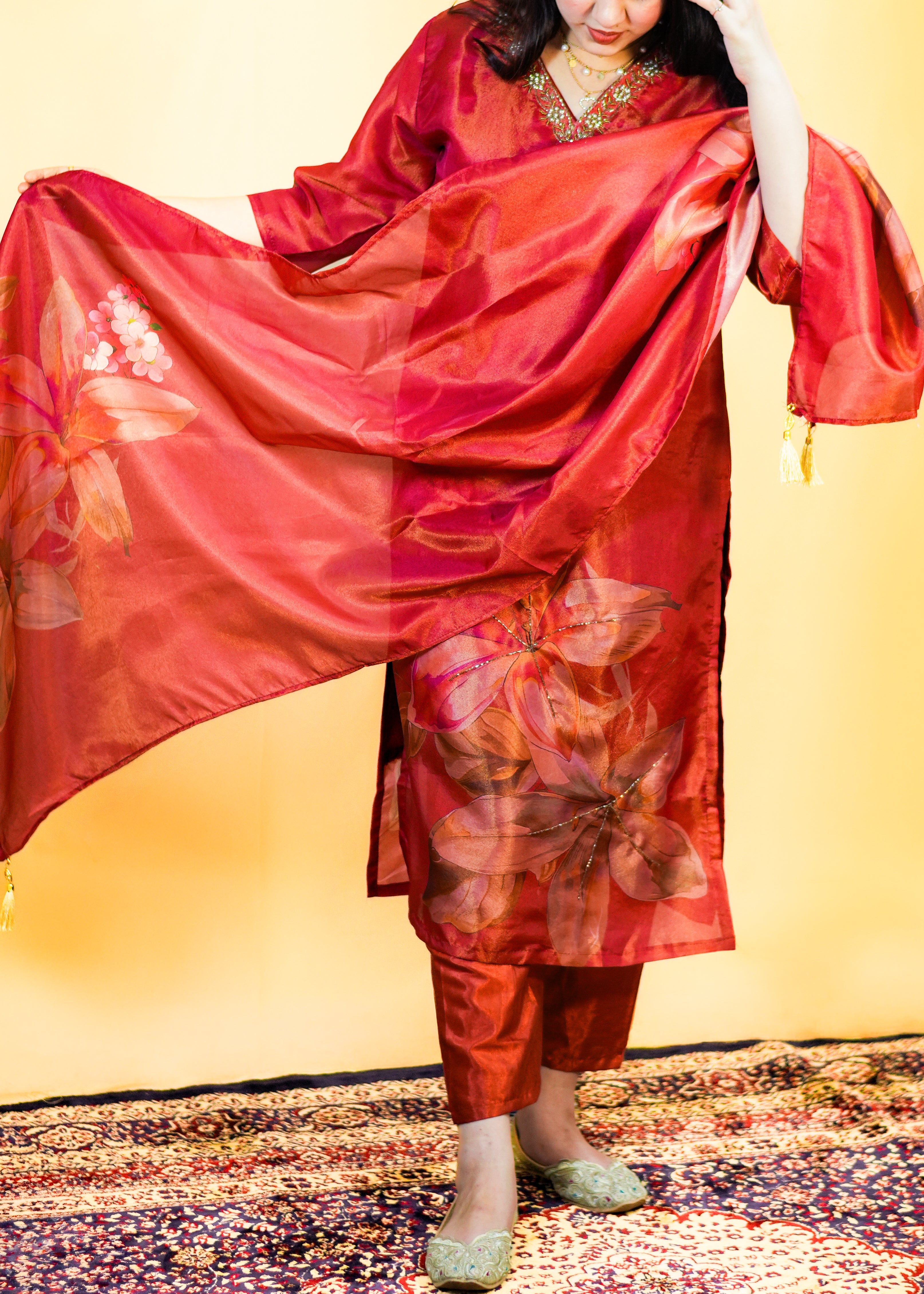 Woman wearing a red traditional outfit with floral patterns on a yellow background