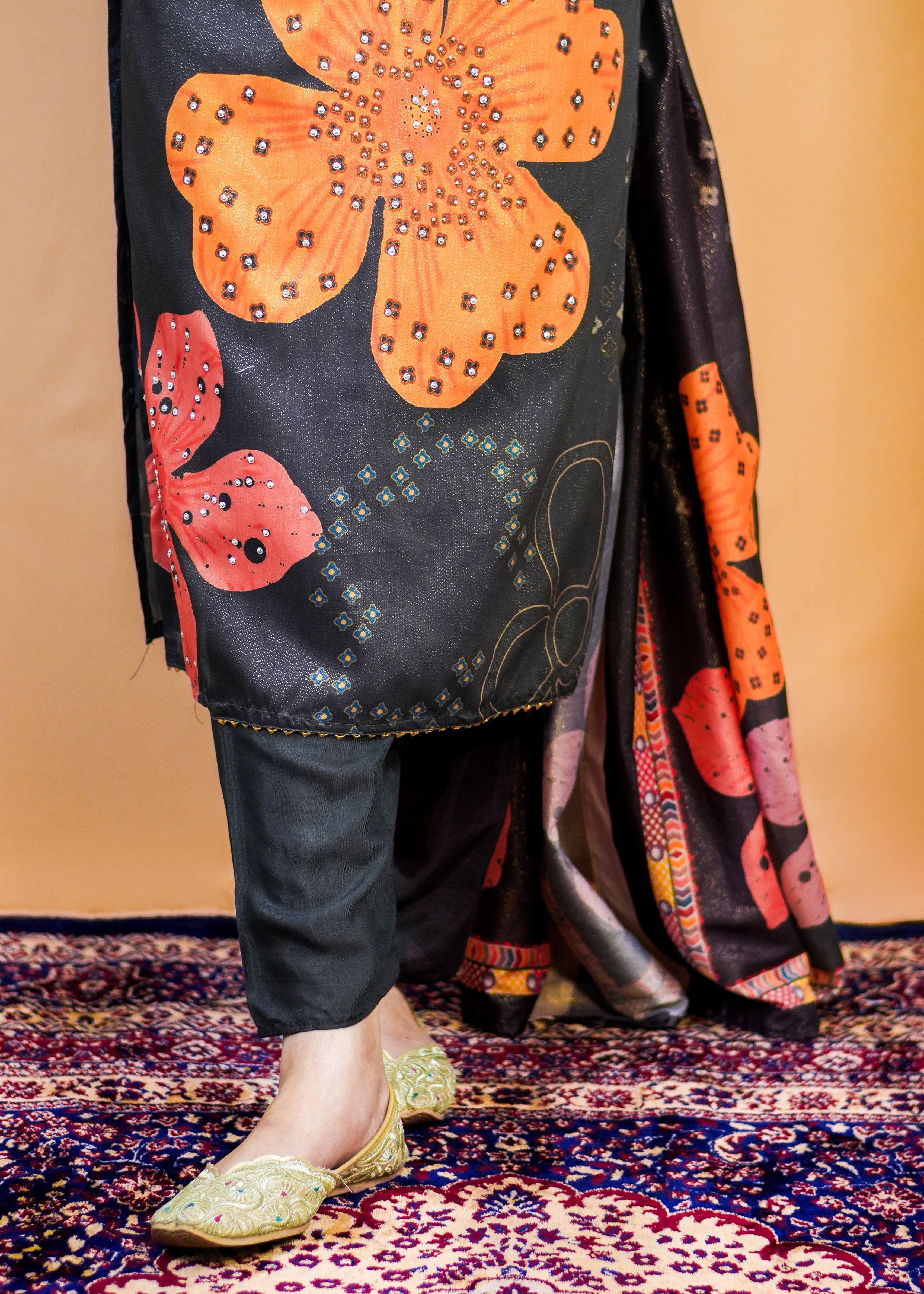 Traditional outfit with floral patterns and embellishments on a patterned rug.