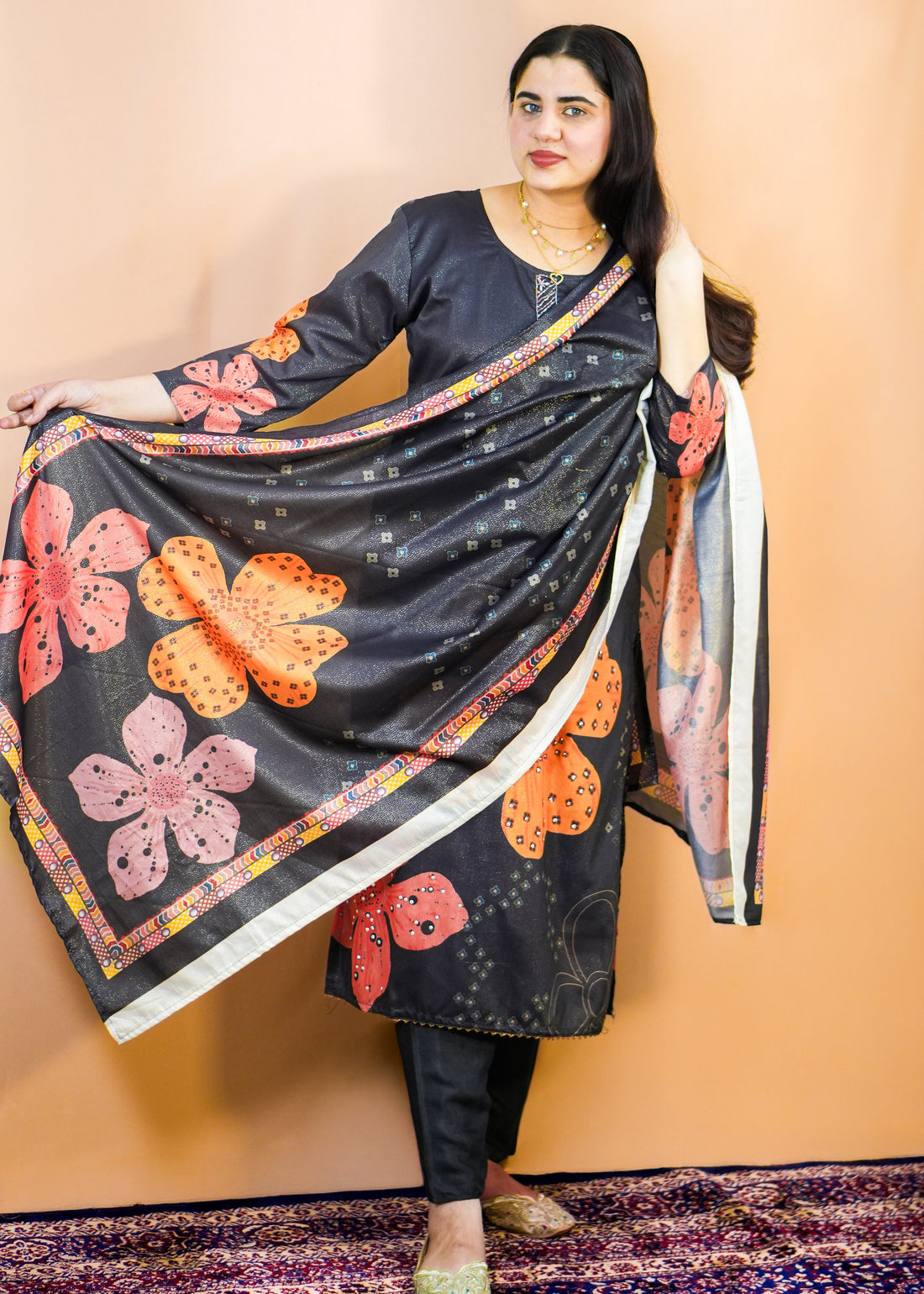 Woman wearing a black floral dress with a matching shawl against a beige background