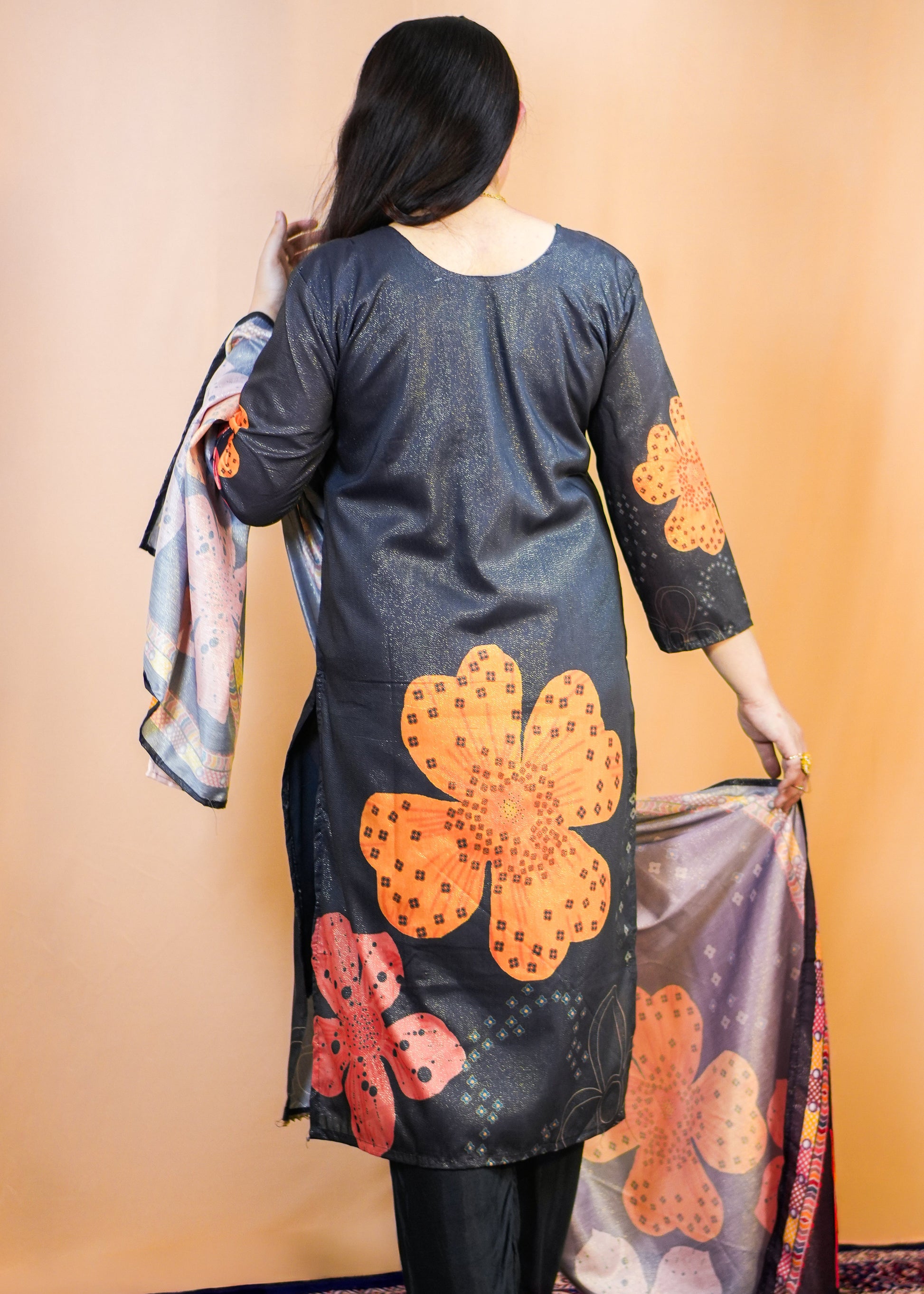 Woman holding a colorful scarf with floral patterns against a beige wall.