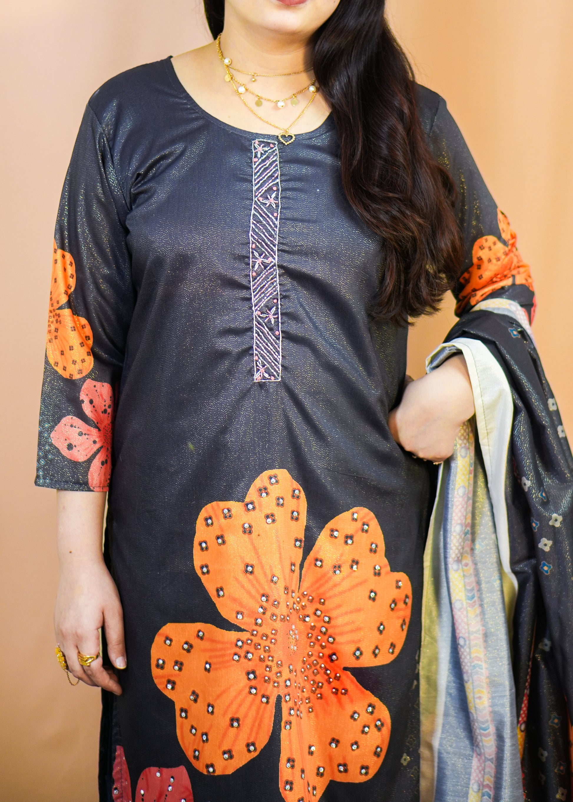 Woman wearing a dark blue kurta with orange floral patterns on a beige background