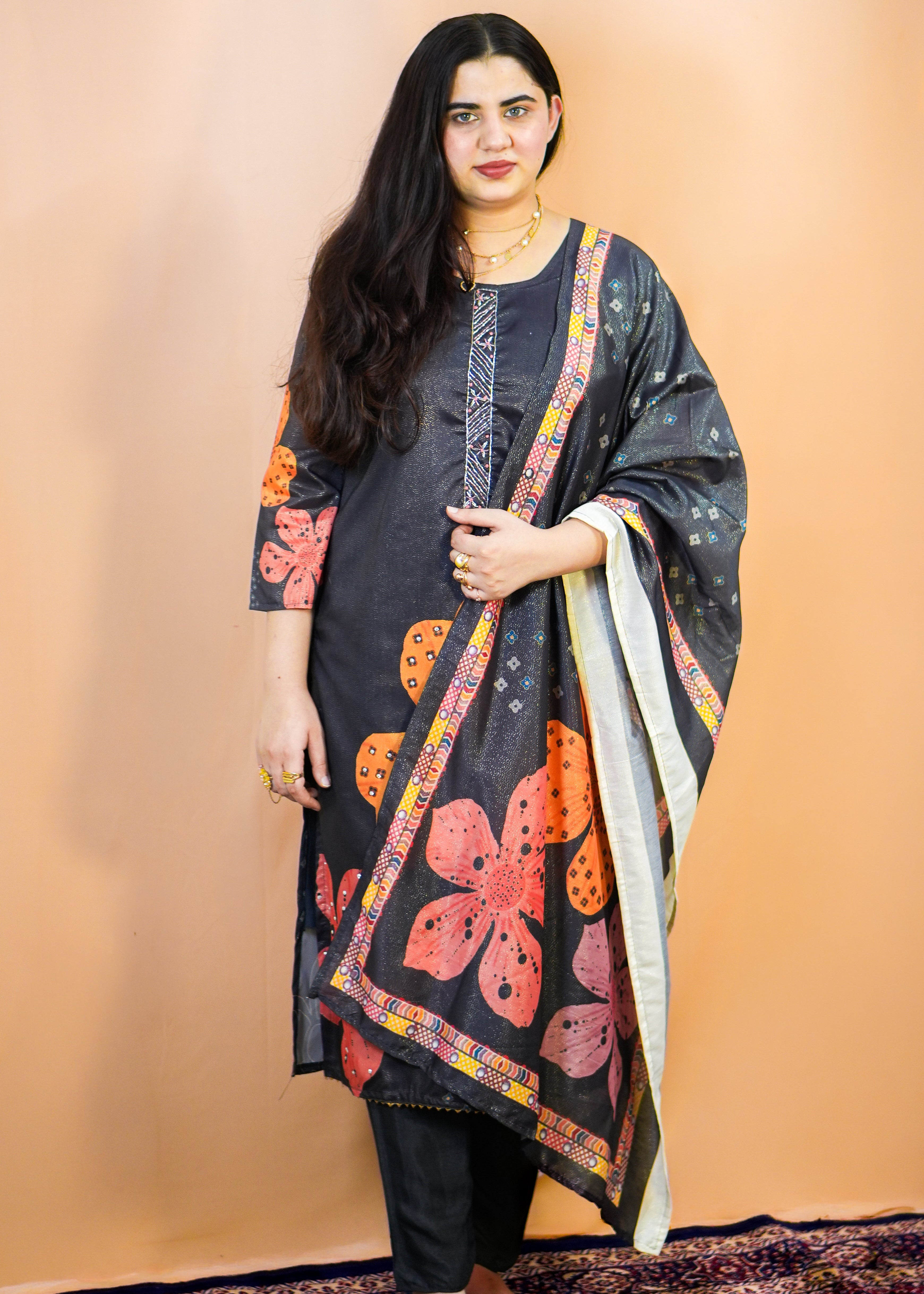 Woman wearing a black floral dress with a matching shawl against a beige background