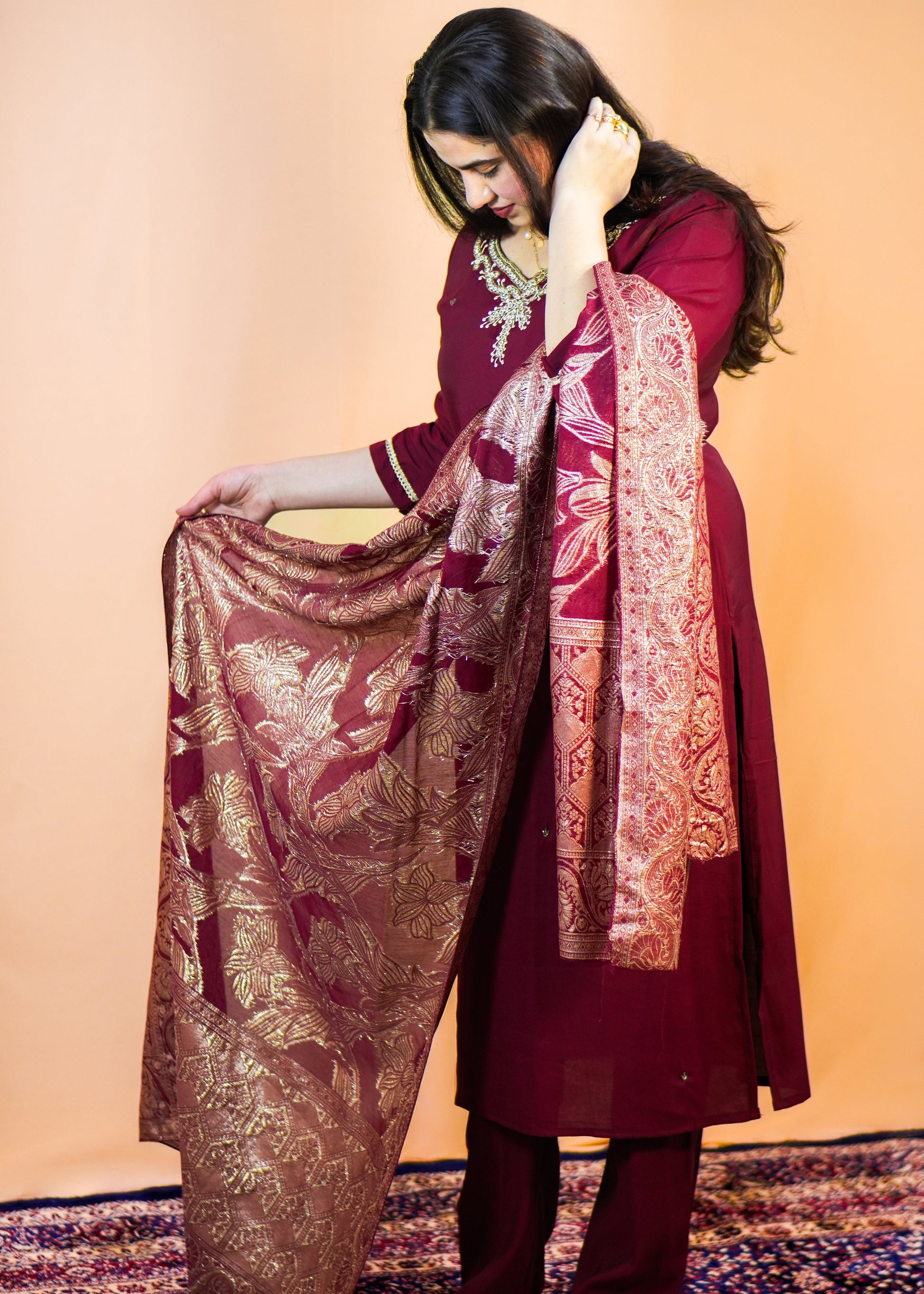 Woman holding a patterned dupatta against a plain background