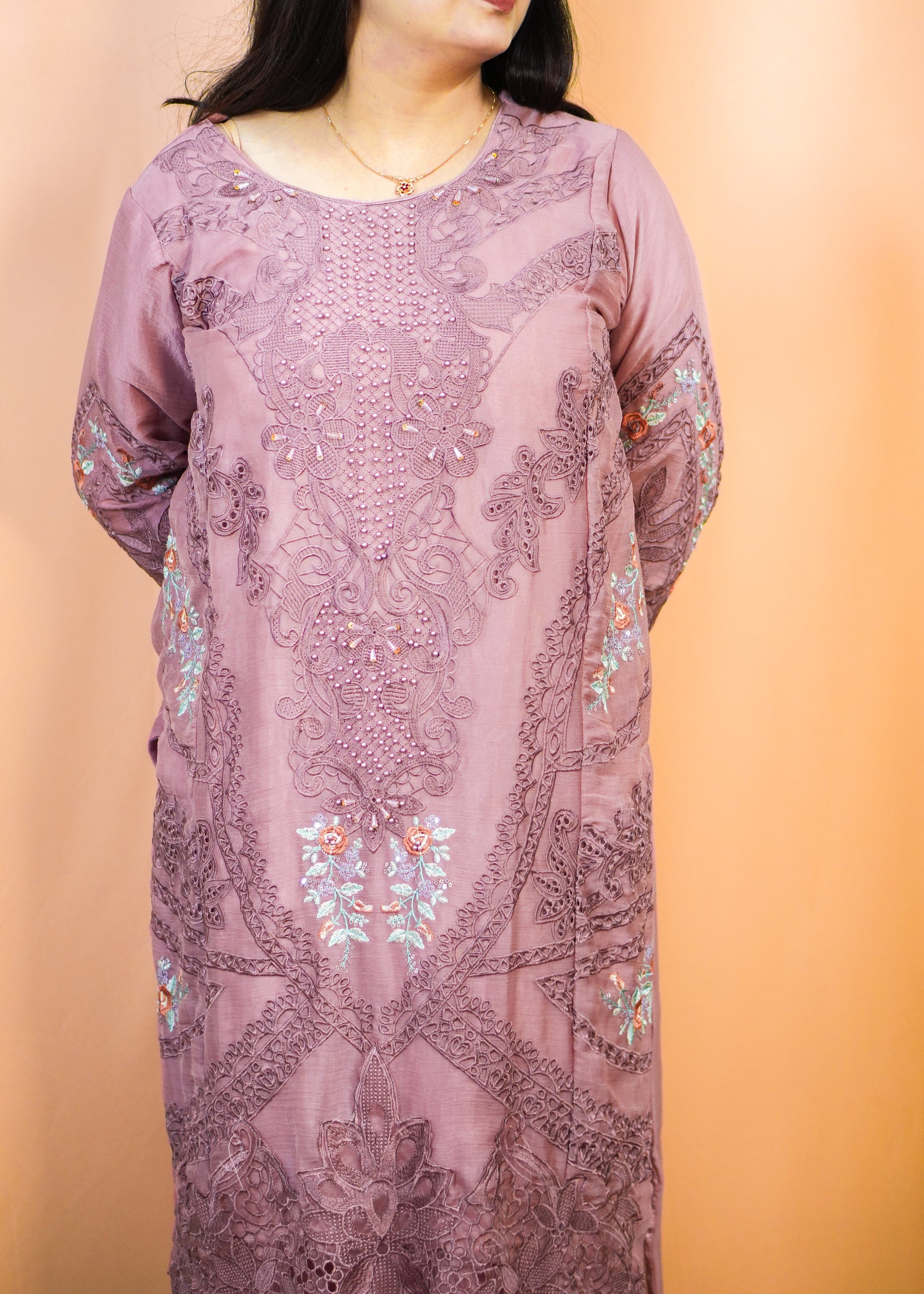 Woman wearing a long, floral-patterned dress against a peach background