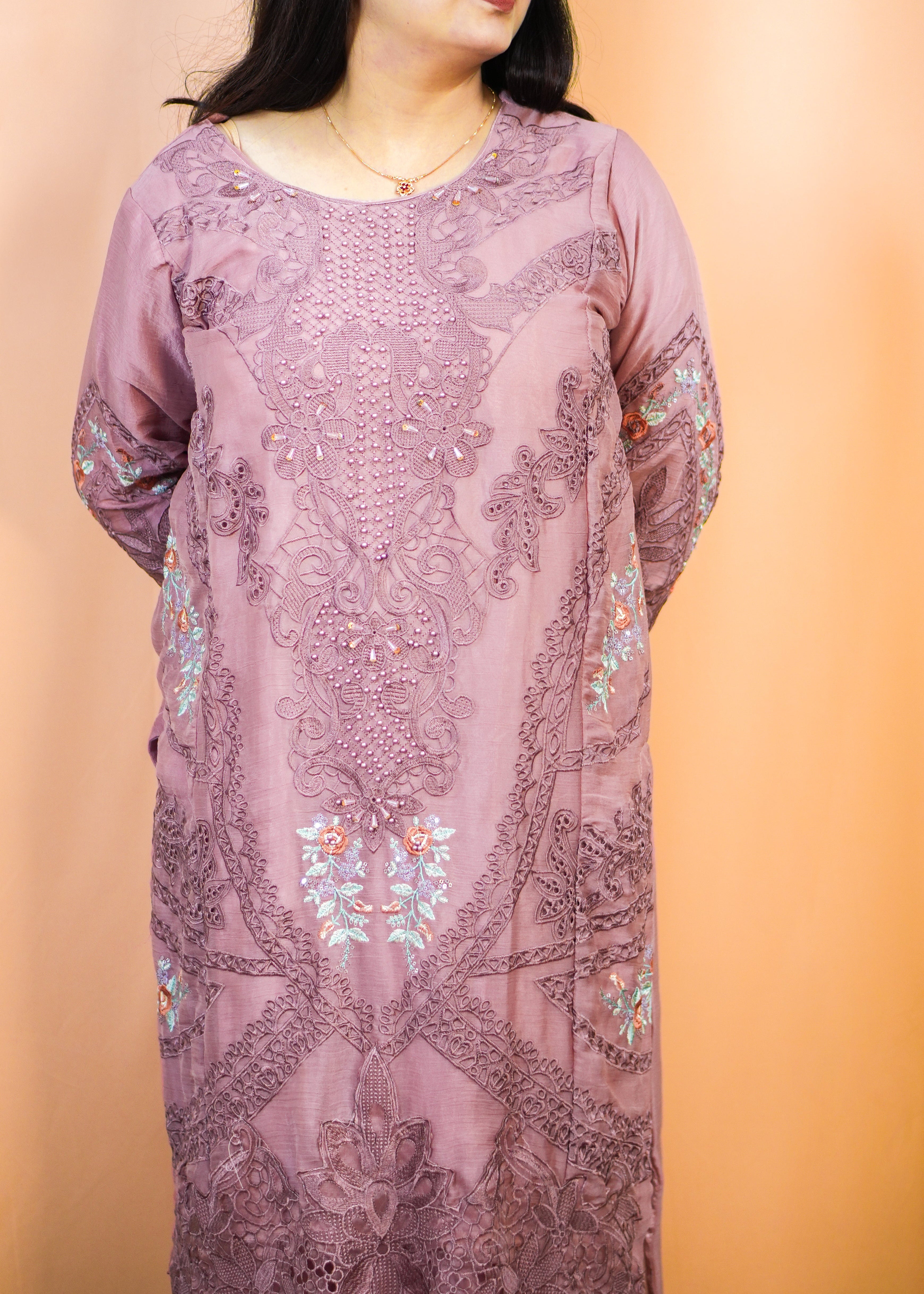 Woman wearing a long, floral-patterned dress against a peach background
