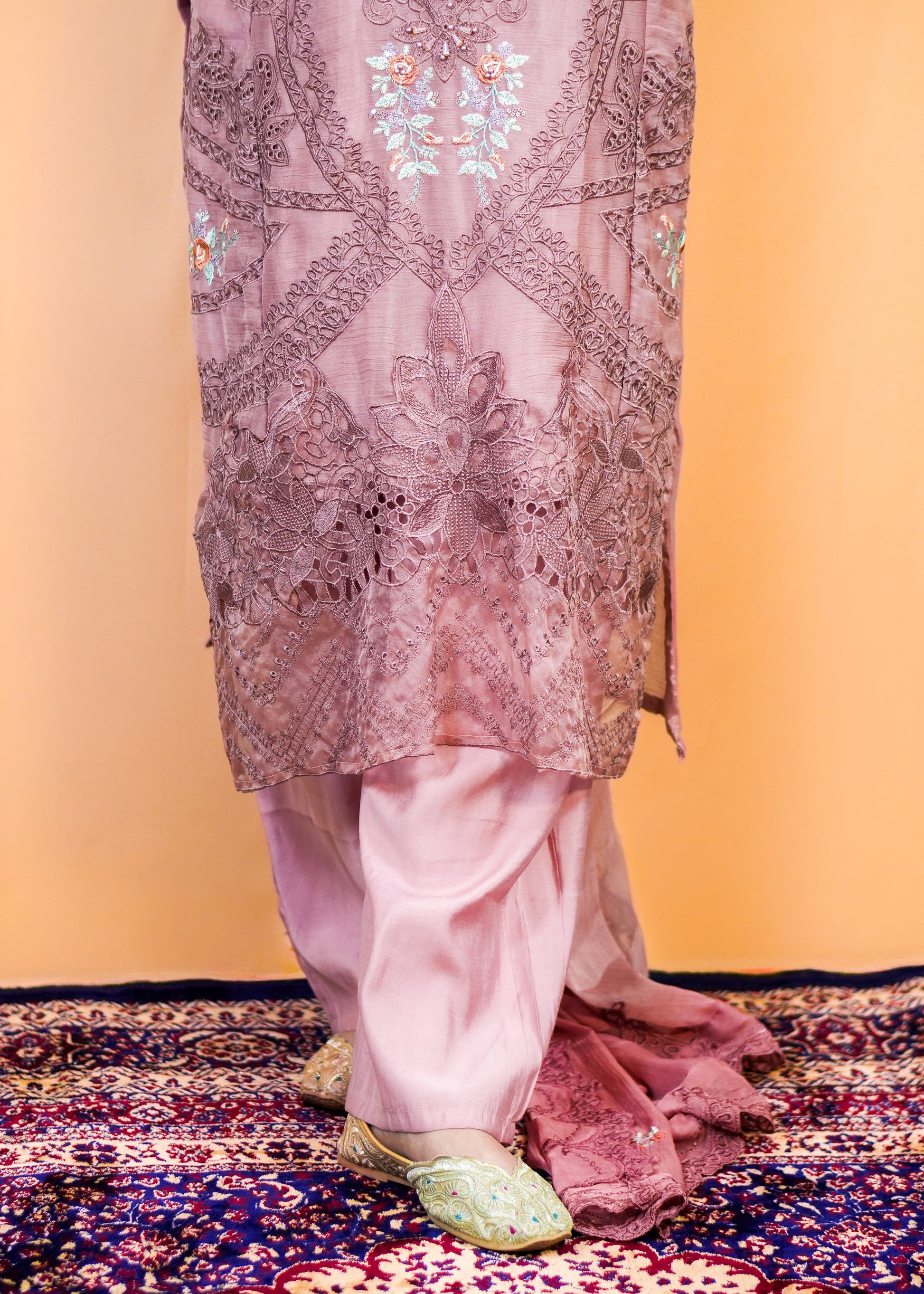 Traditional outfit with intricate embroidery on a patterned rug