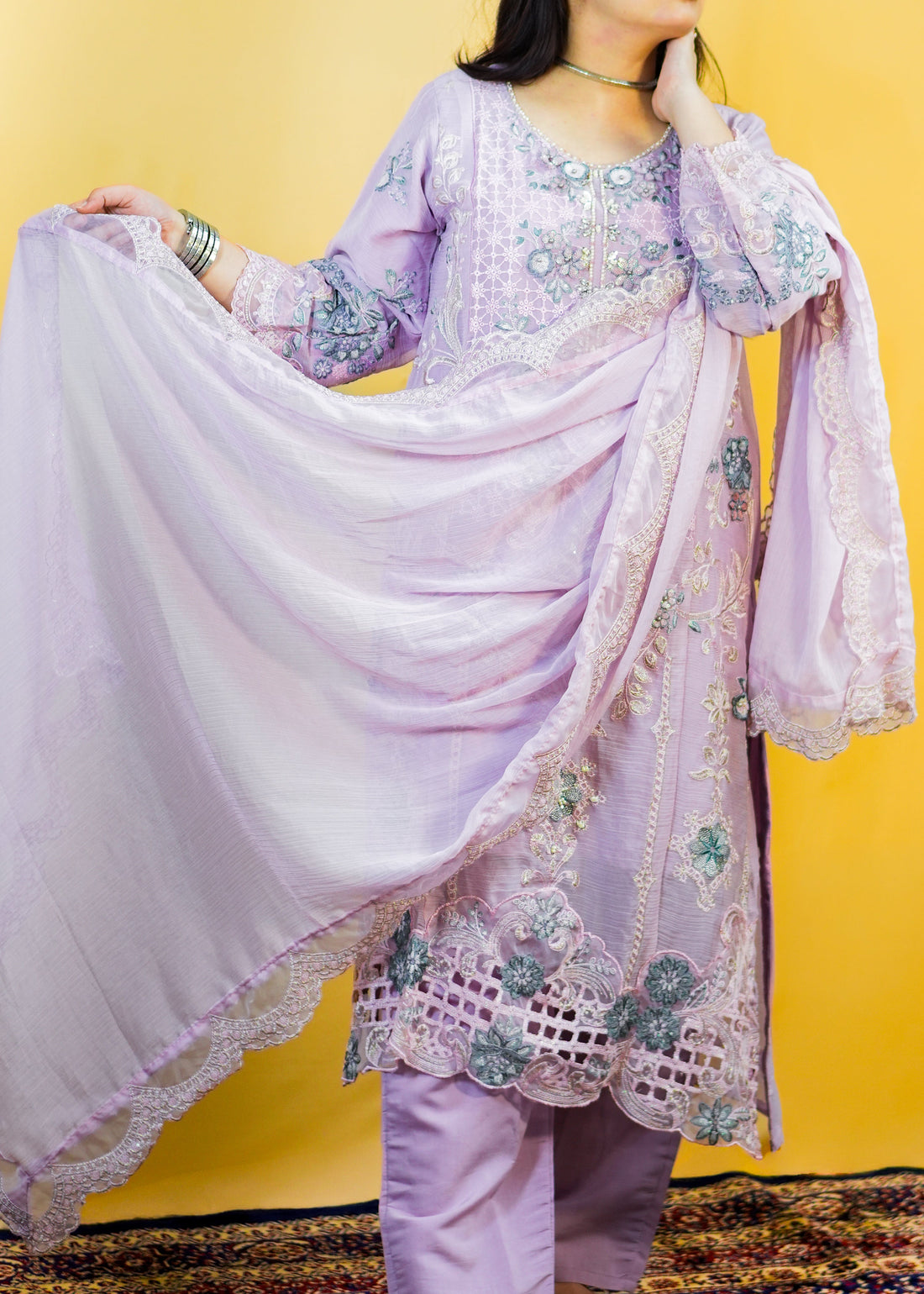 Woman wearing a light purple embroidered outfit with a matching dupatta against a yellow background
