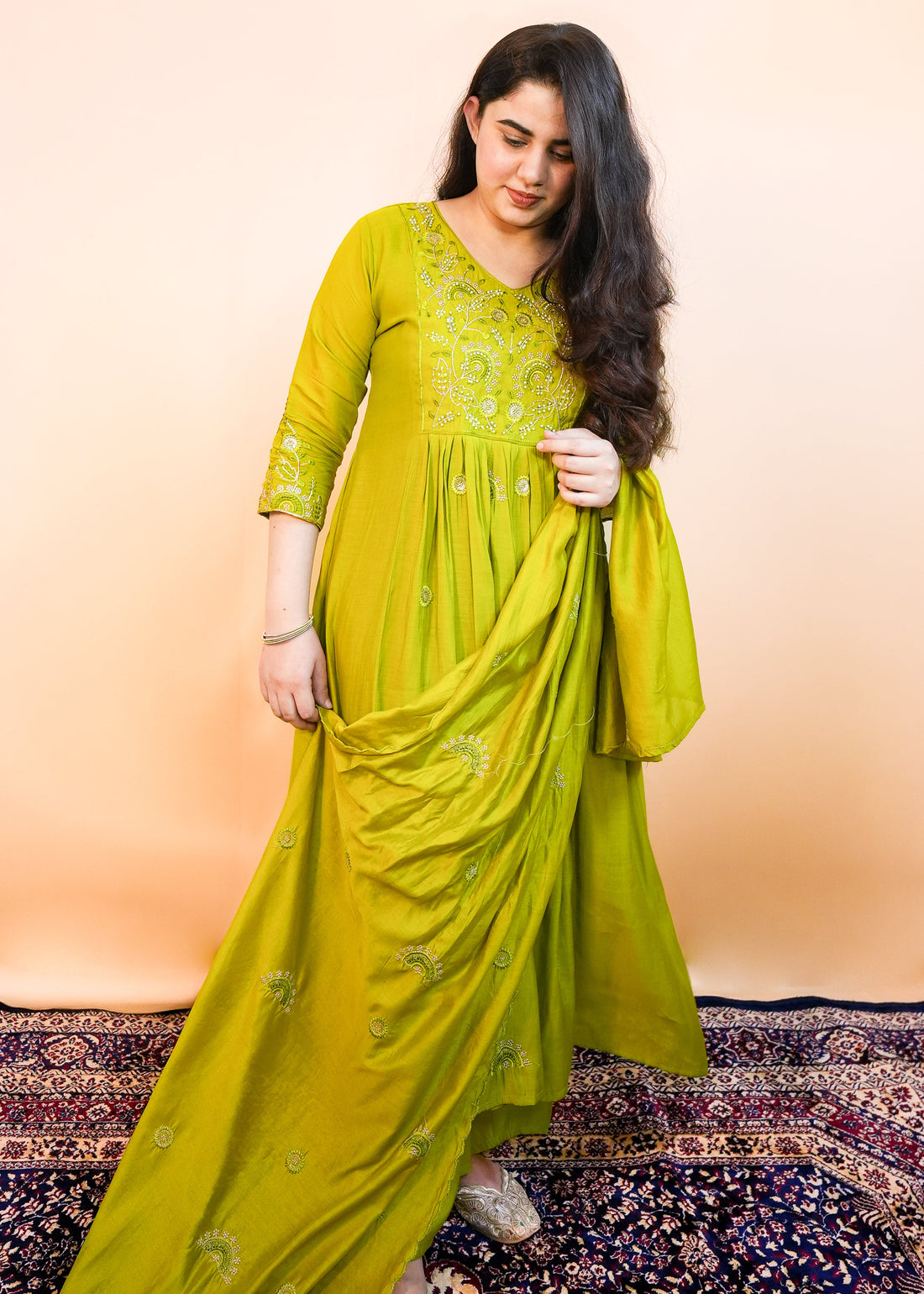 Woman wearing a green saree with a pattern against a beige background