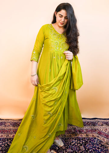 Woman wearing a green saree with a pattern against a beige background