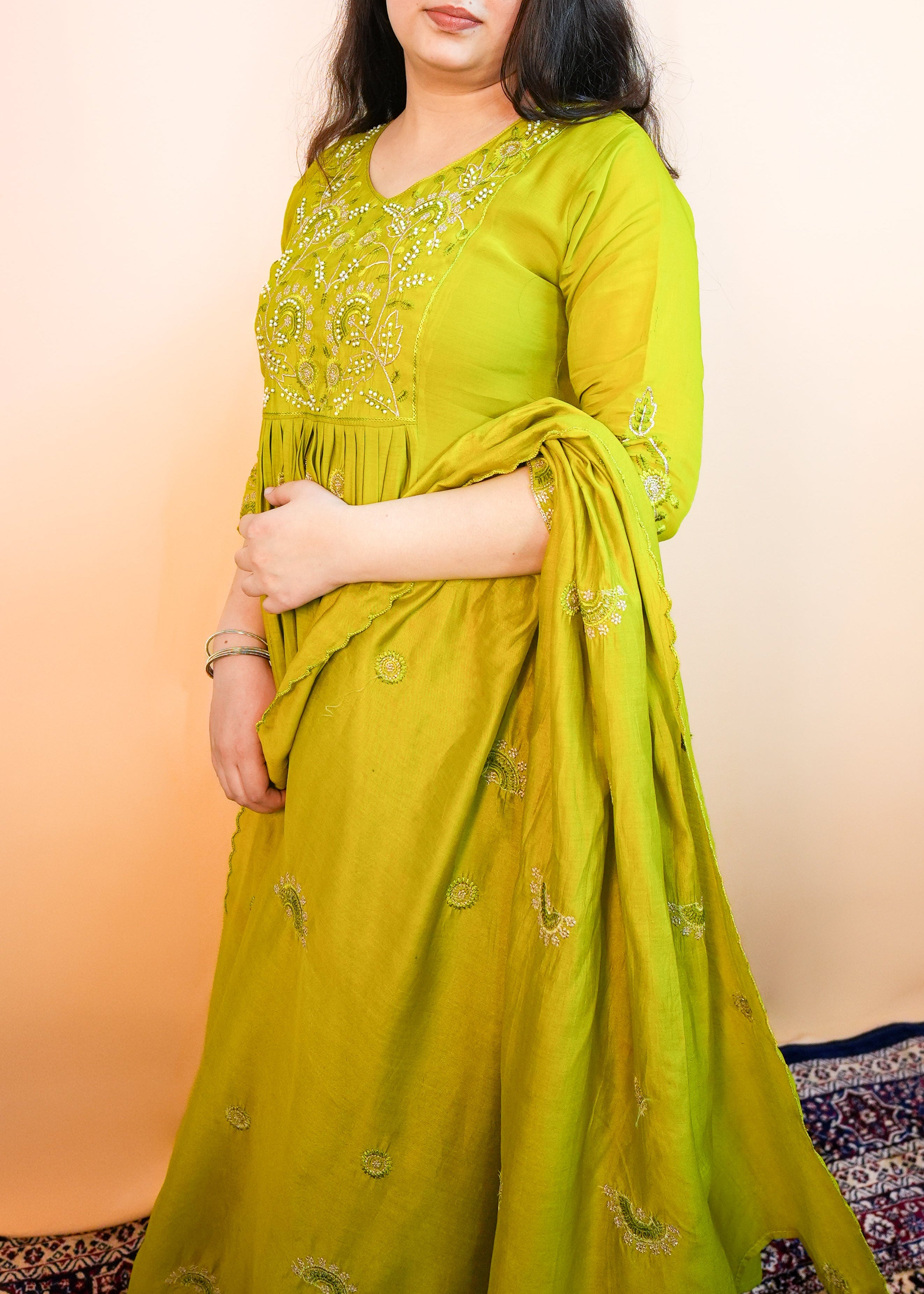 Woman wearing a green traditional outfit with a plain background