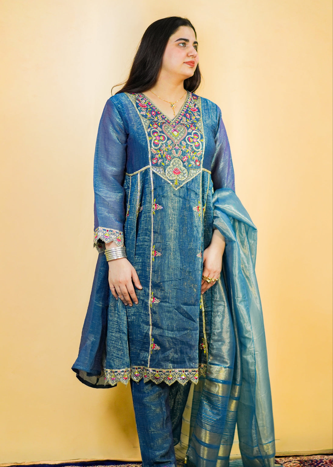 Woman wearing a blue embroidered traditional outfit on a yellow background