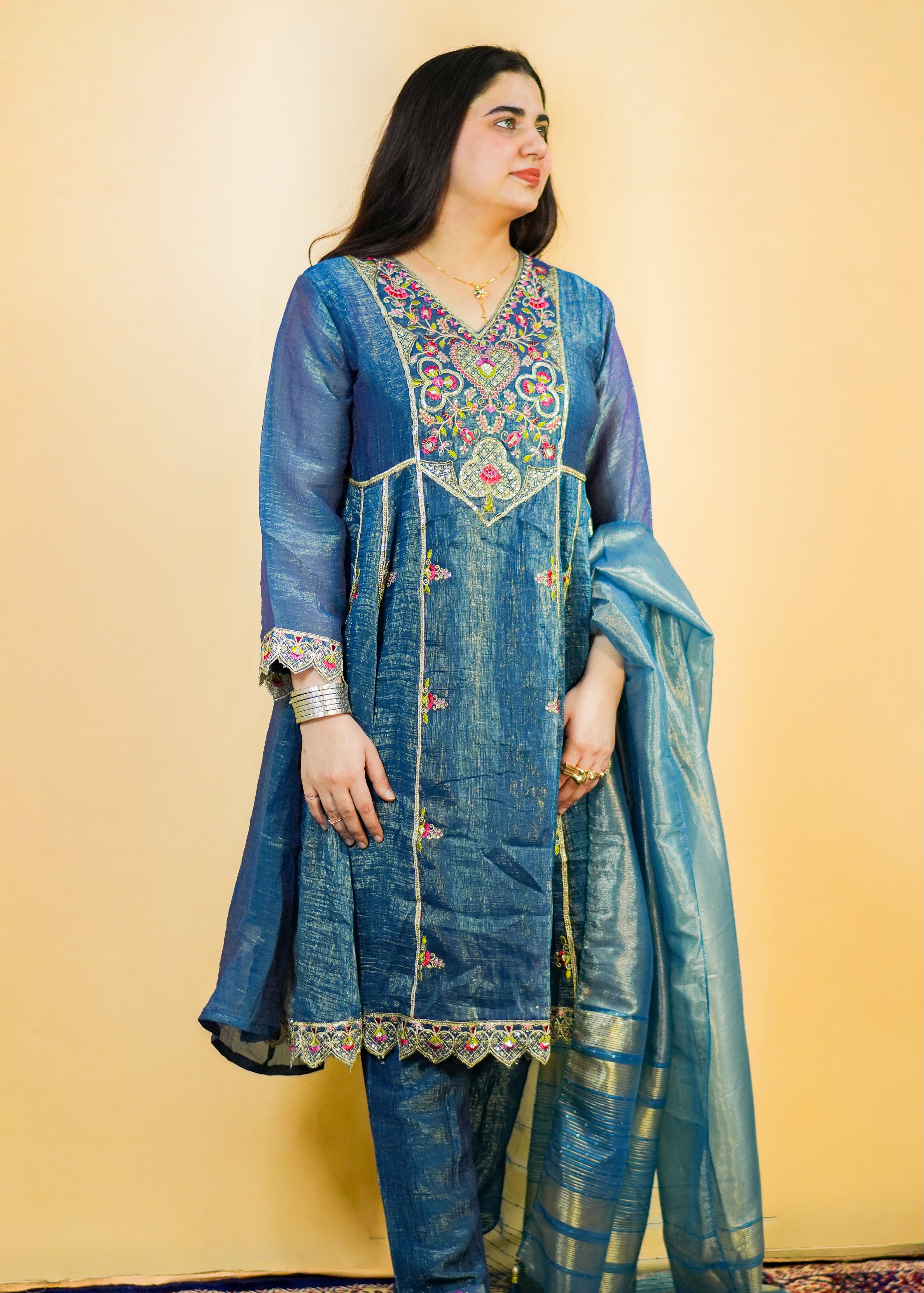 Woman wearing a blue embroidered traditional outfit on a yellow background