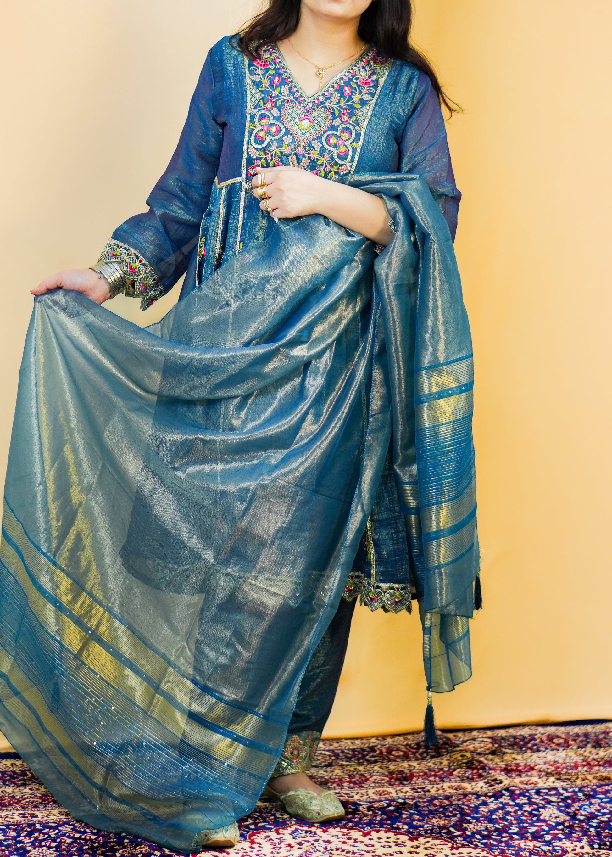 Woman wearing a blue saree with a colorful blouse against a yellow background