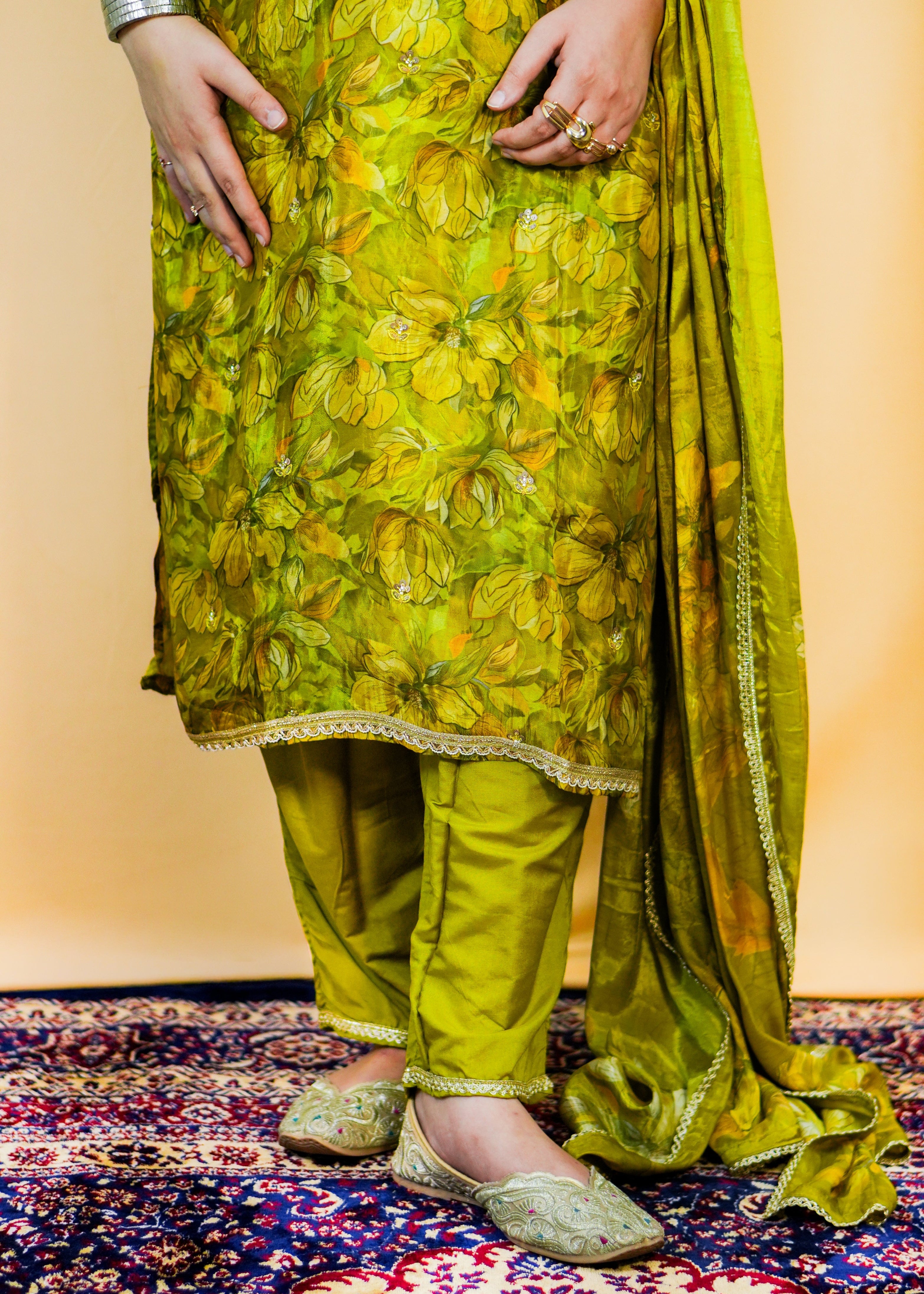 Person wearing a green floral outfit on a patterned rug
