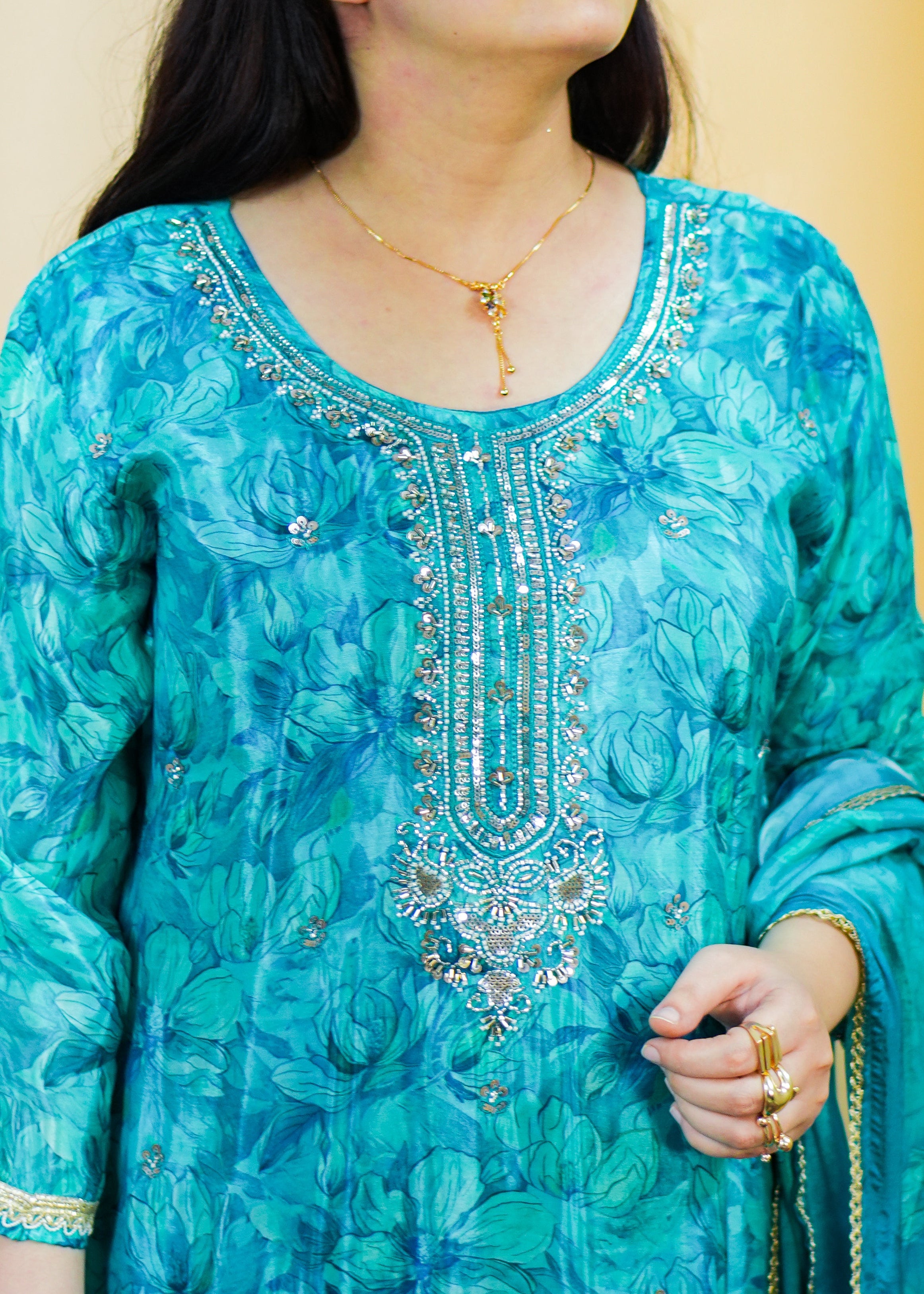 Woman wearing a blue embroidered traditional outfit against a yellow background