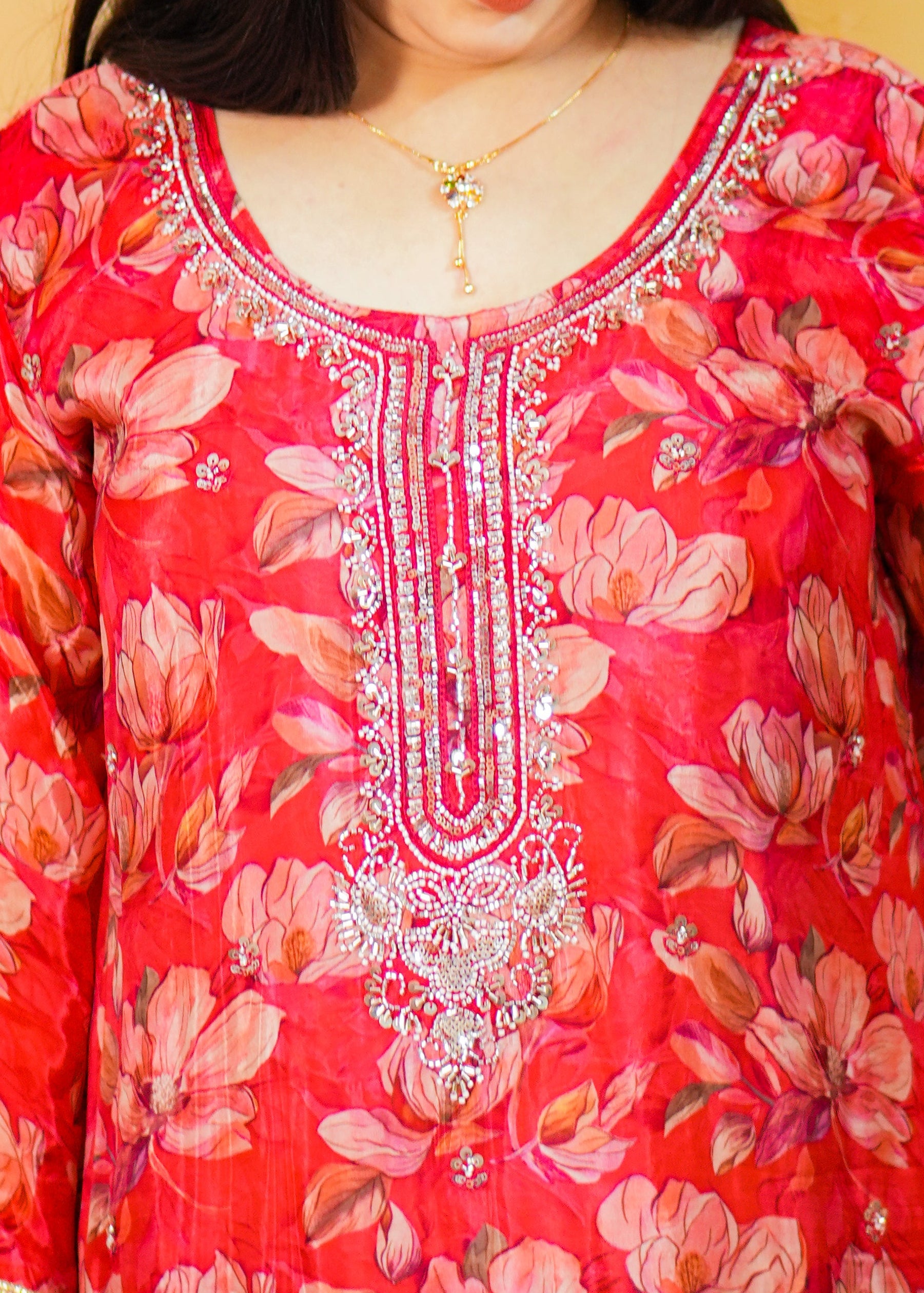 Woman wearing a red floral dress with intricate patterns on a yellow background