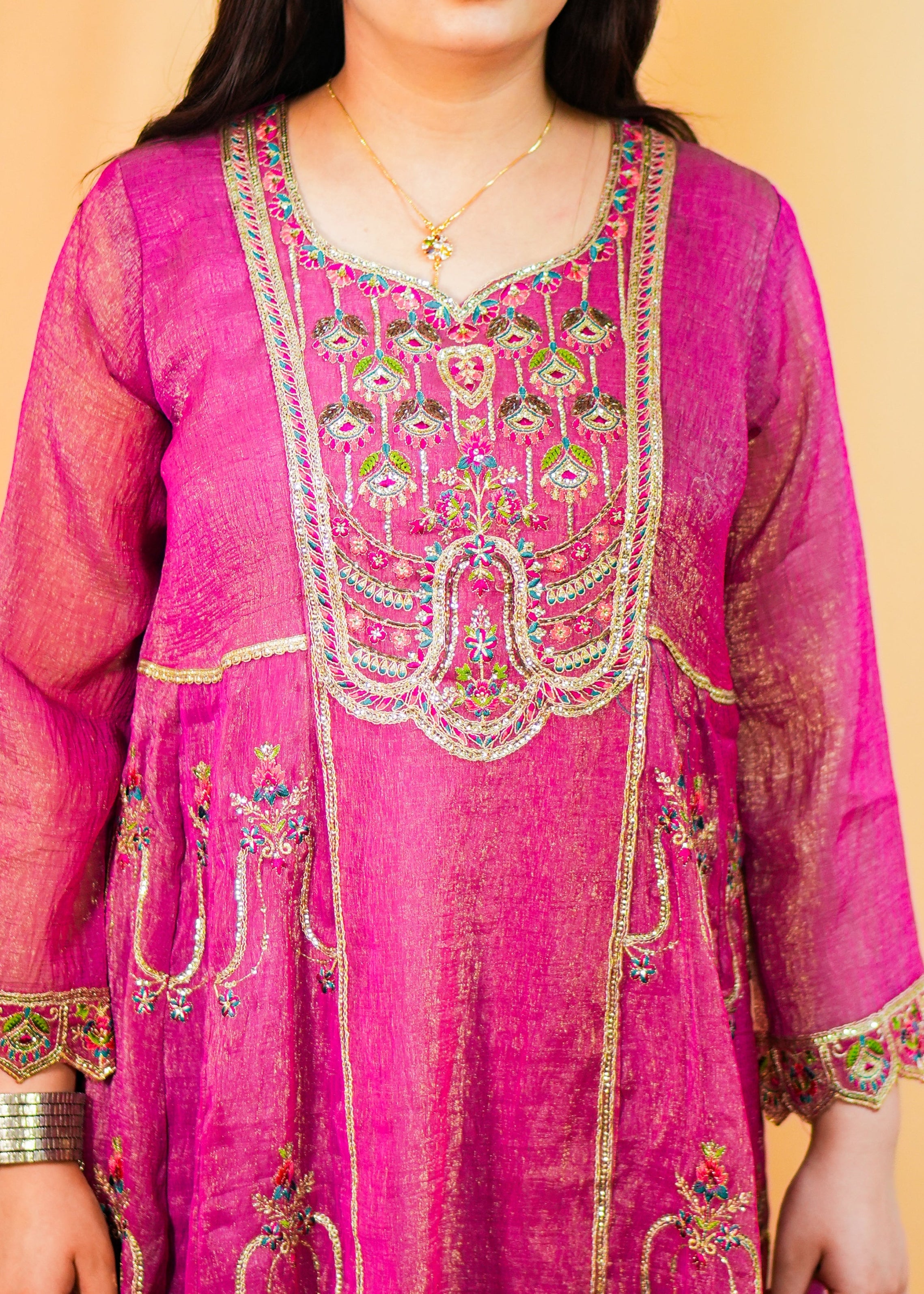 Woman wearing a pink embroidered traditional outfit against an orange background