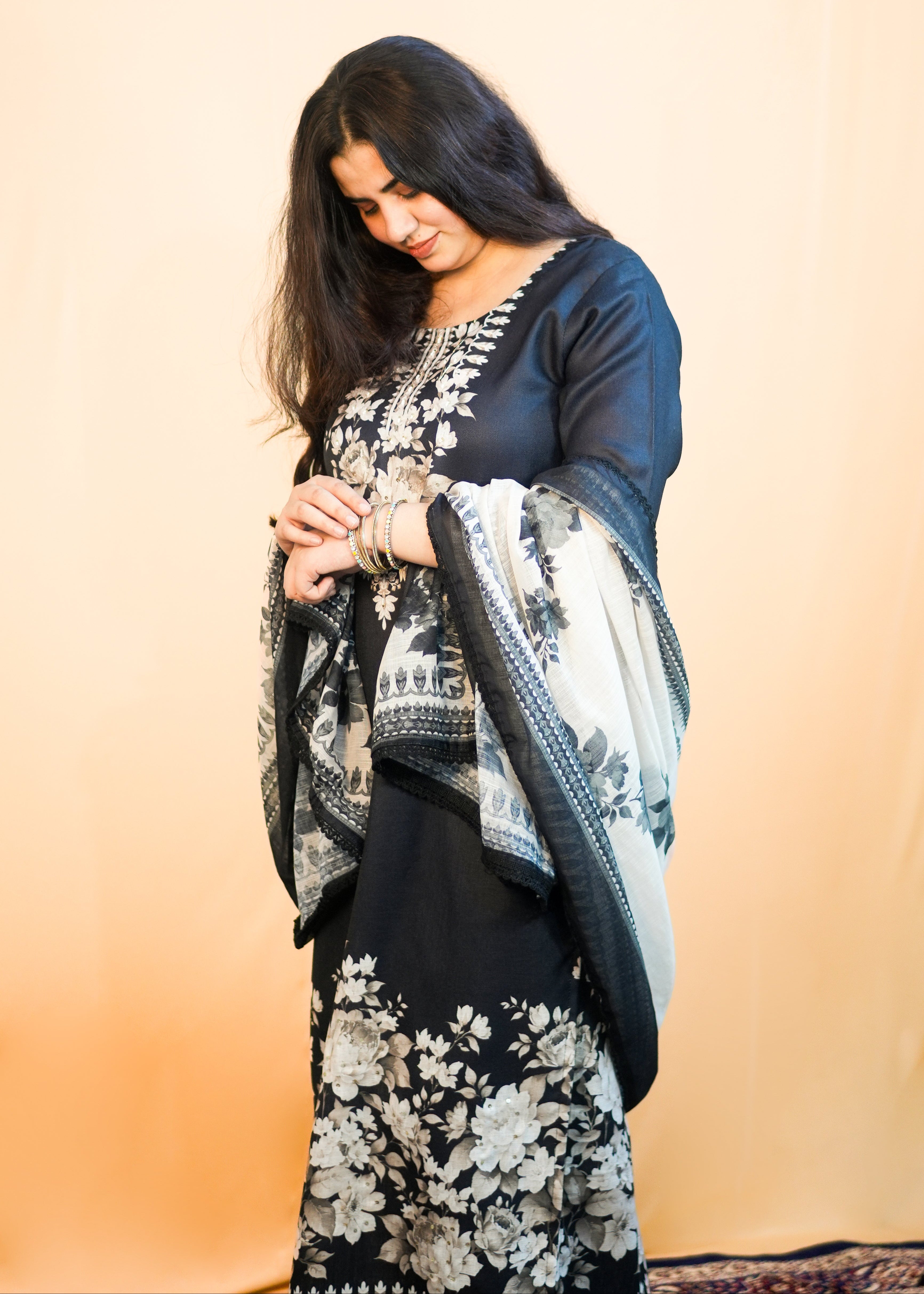 Woman wearing a floral saree with a dark blouse against a beige background