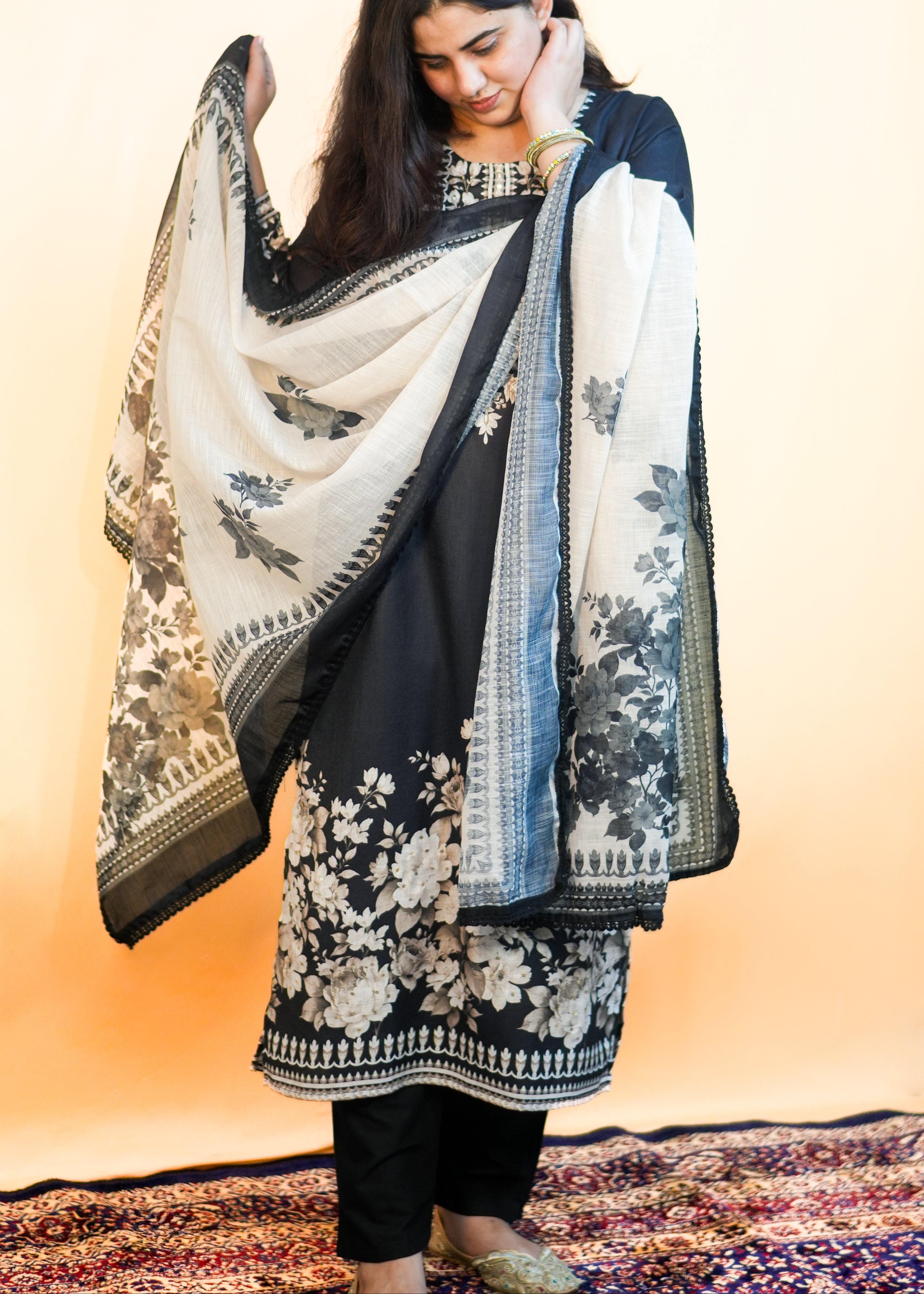 Woman wearing a black and white floral patterned dupatta against a warm-toned background
