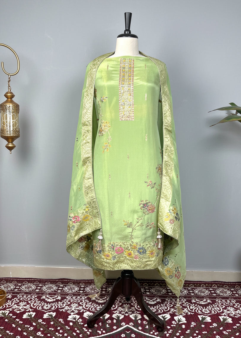 Green embroidered dress on a mannequin against a decorative wall with a patterned rug.