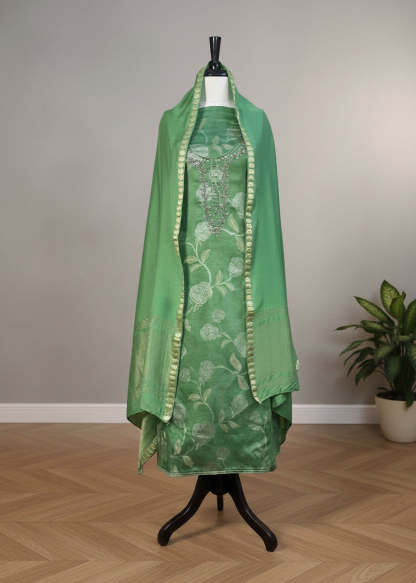 Green dress with floral pattern on a mannequin against a beige wall.