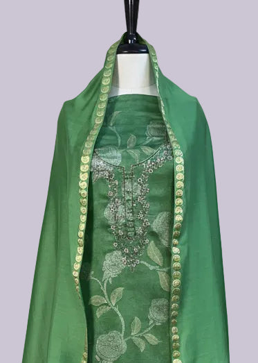 Green dress with floral pattern on a mannequin against a beige wall.
