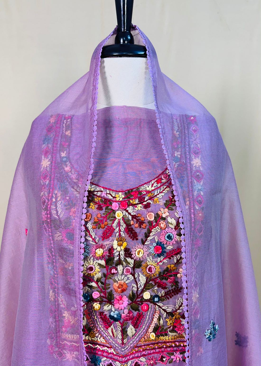 Lavender traditional outfit with floral embroidery on a mannequin against a white wall.