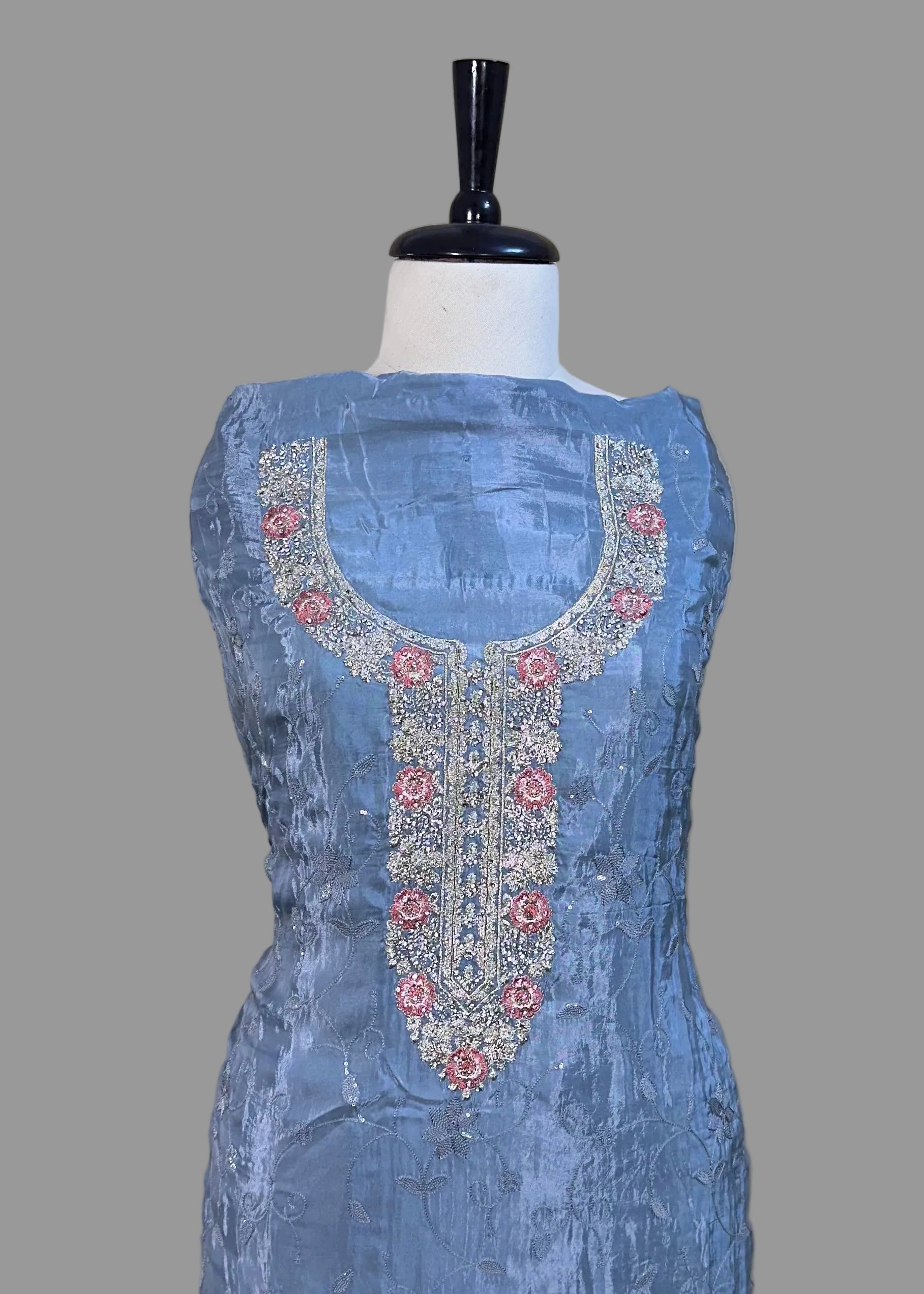 Blue embroidered dress on a mannequin against a beige background