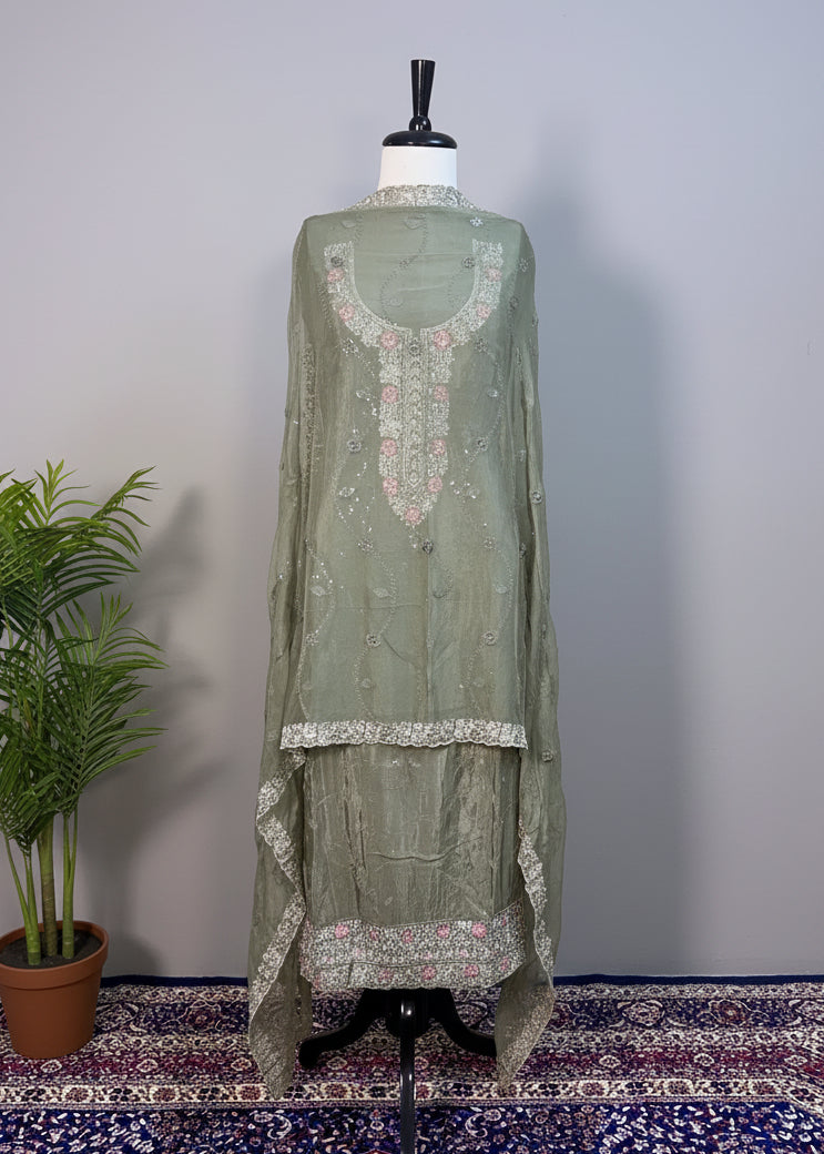 Green embroidered dress on a mannequin against a beige curtain